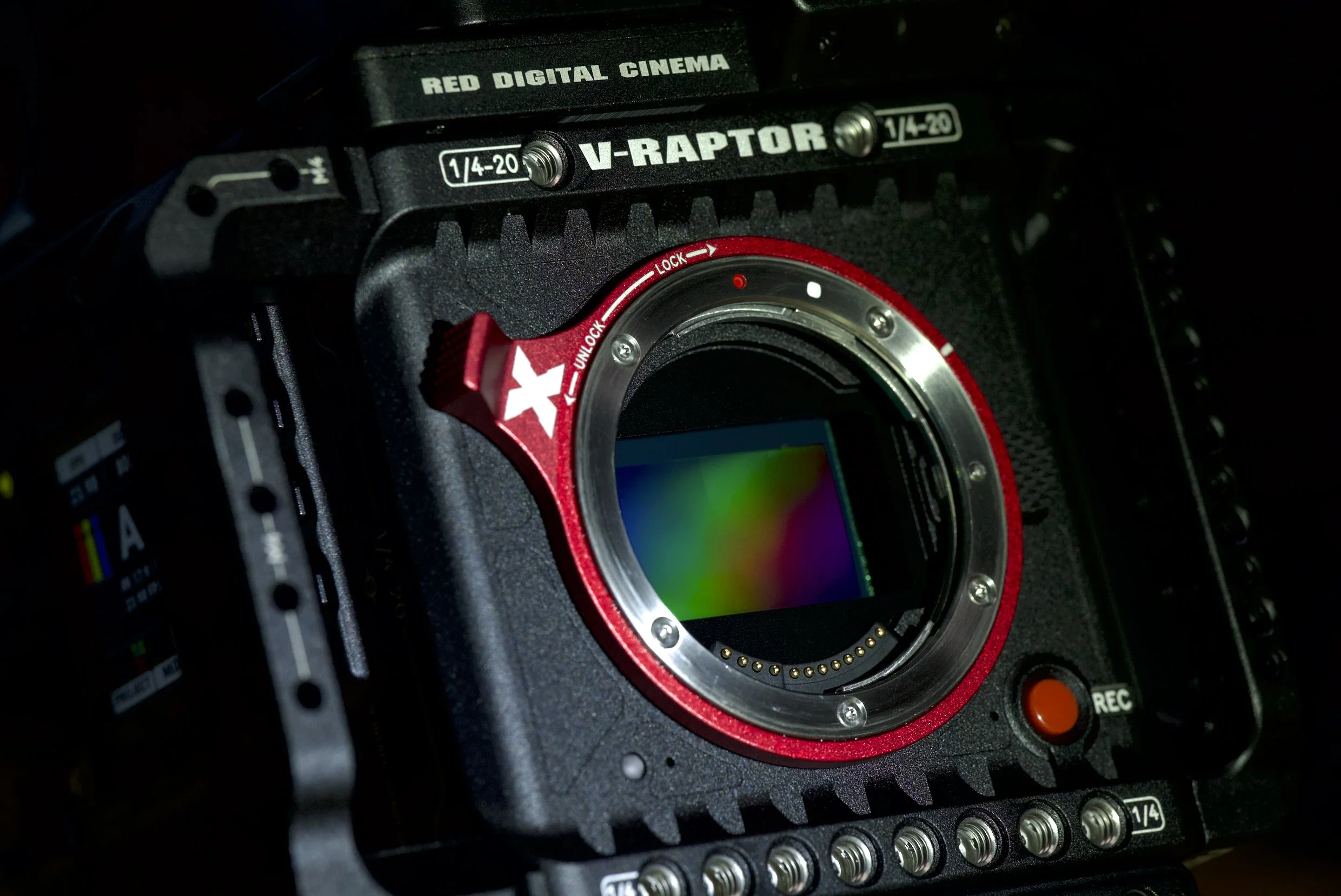 Close-up of a professional cinema camera with a sensor visible inside the lens mount, labeled 'V-Raptor', with various controls and markings for settings.