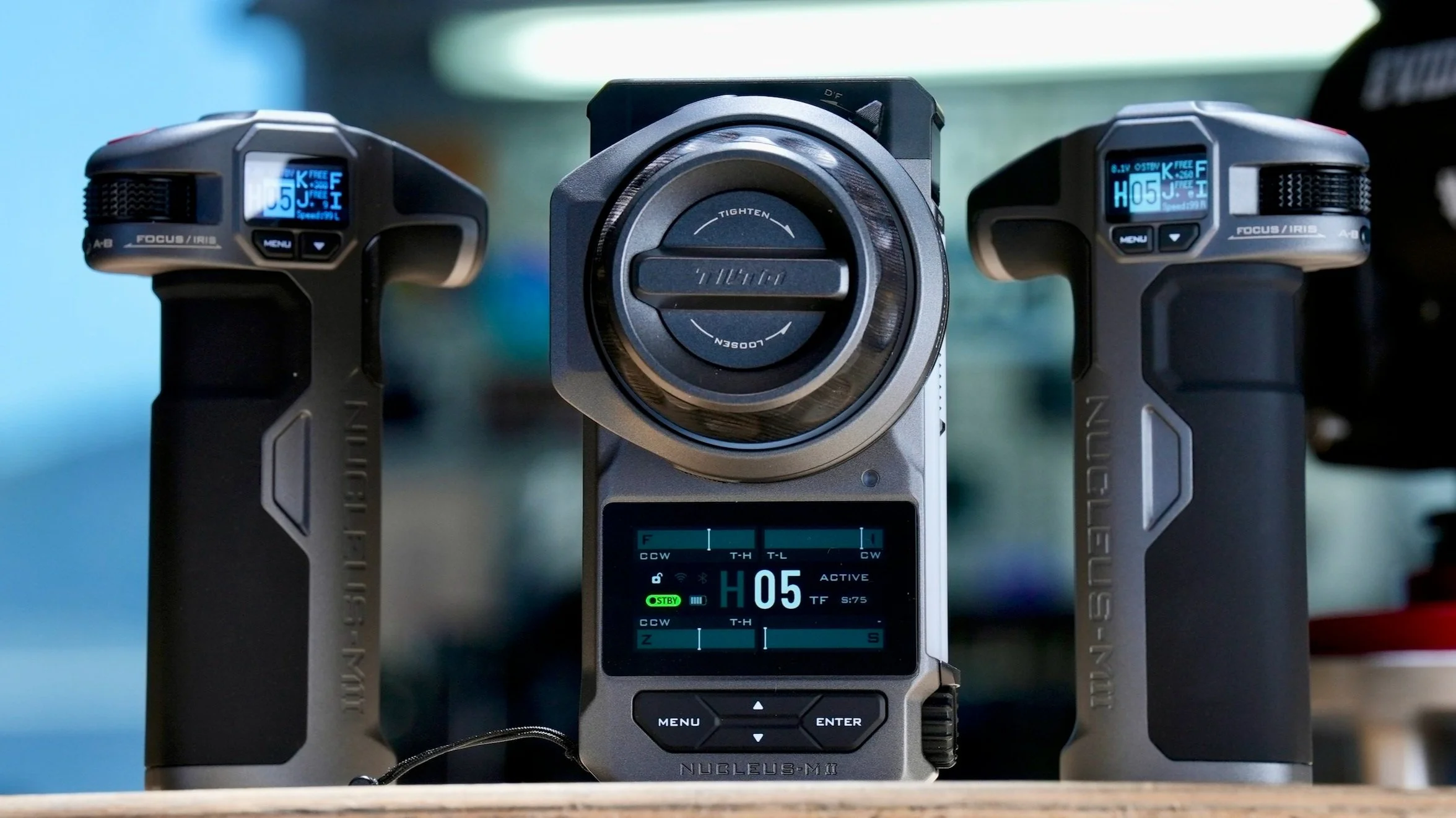 A camera with a large lens in the middle flanked by two handheld remote controllers with digital displays.