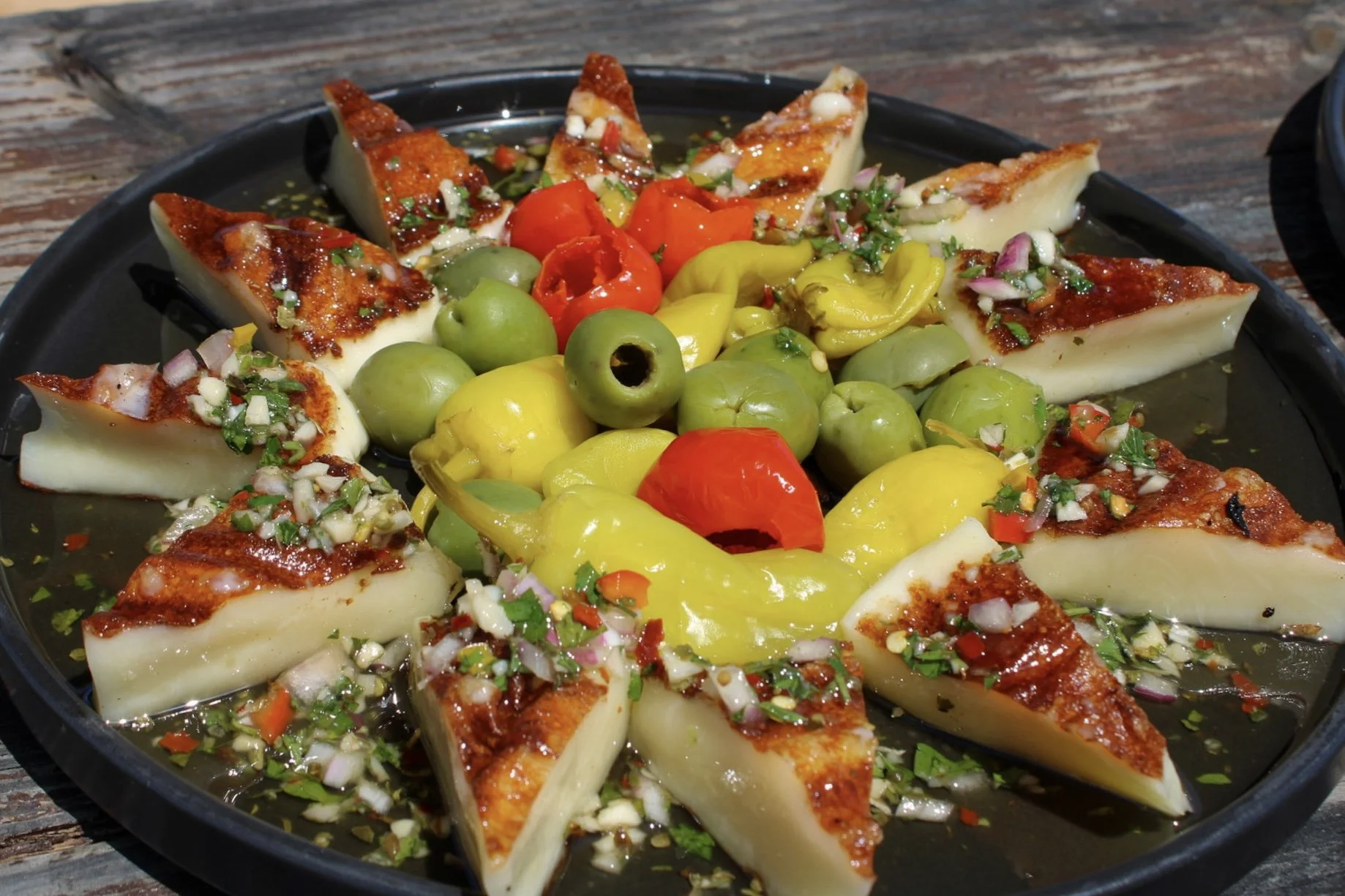 Plated Provoletta surrounded by a colorful assortment of house-pickled vegetables.