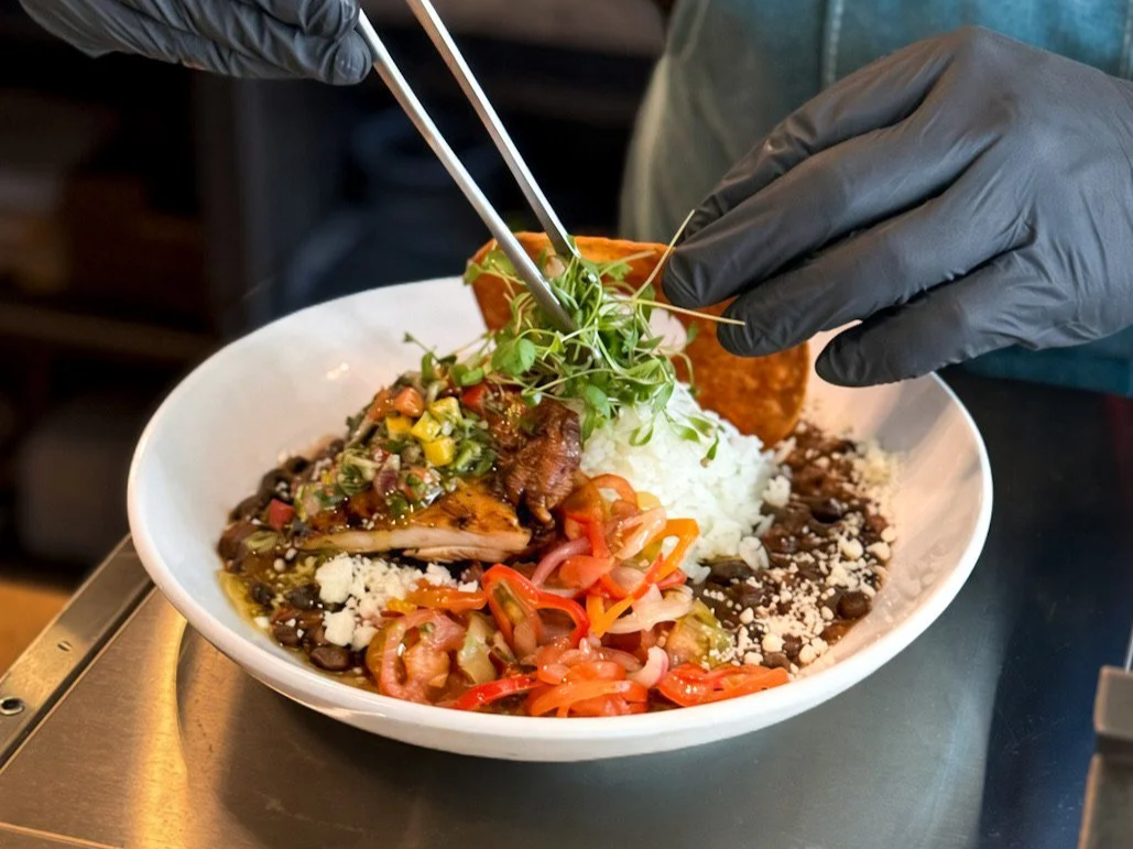 Chef at Asado Life Garnishing an Asado Bowl with micro cilantro