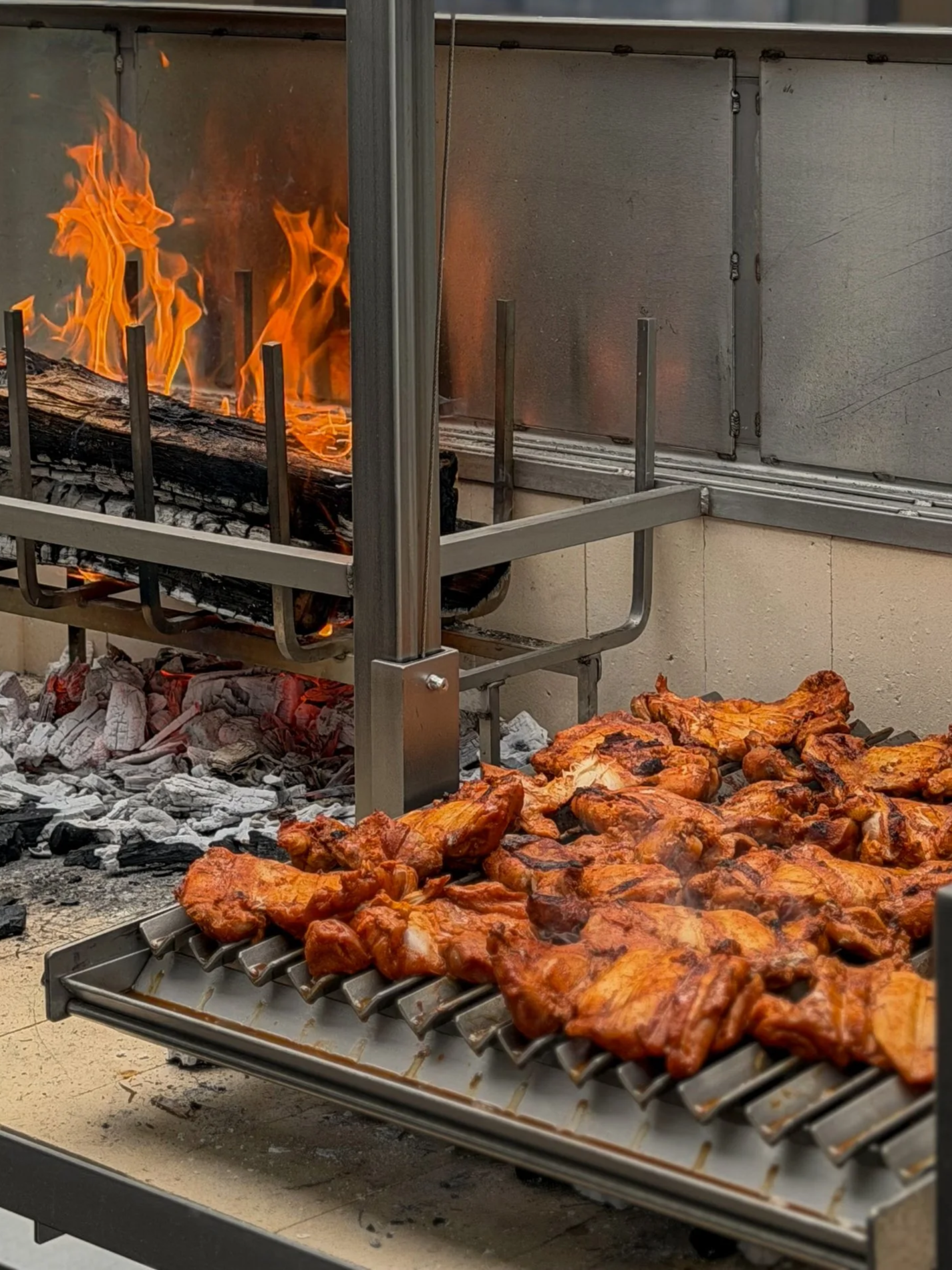 Signature spiced chicken thigh cooking over live fire on an Urban Asado grill at Asado Life Jacksonville.
