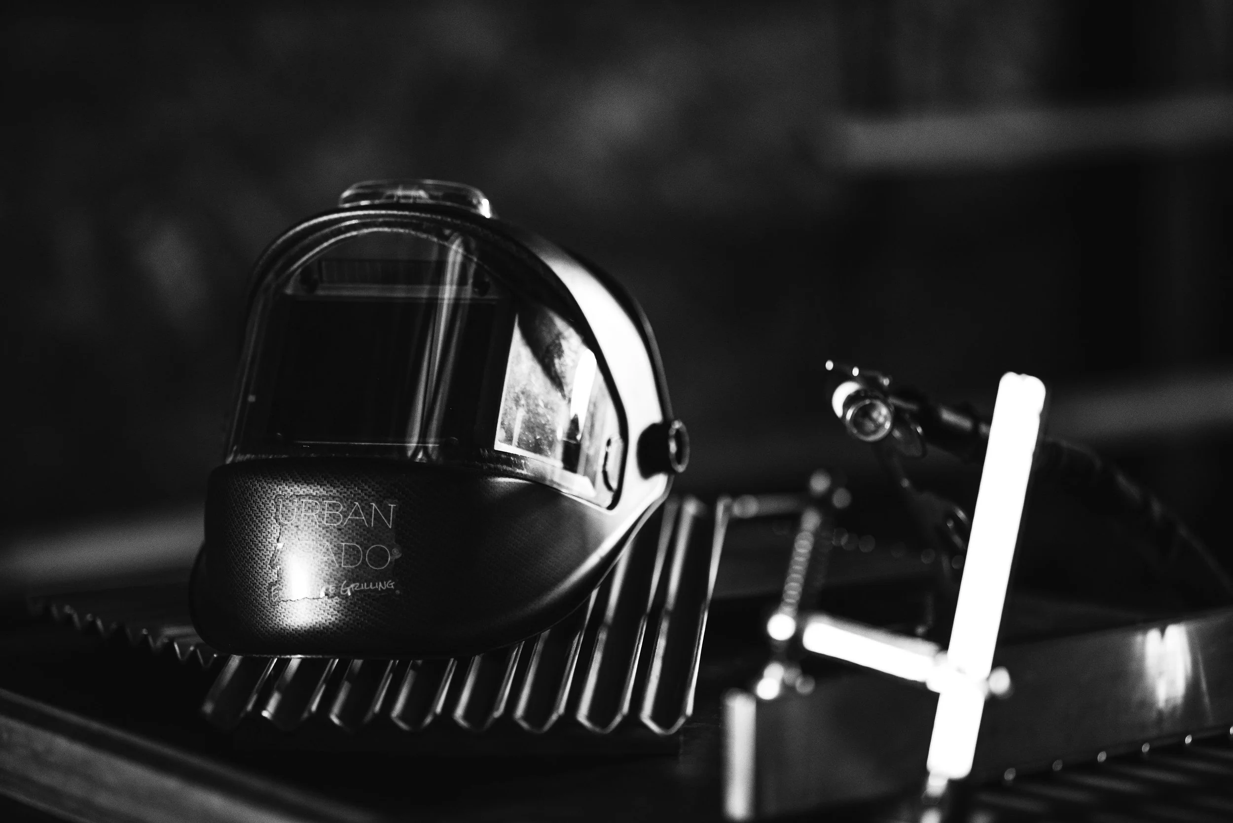 Black and white view of a welding helmet inside Urban Asado, Asado Life’s grill fabrication studio, showcasing the craftsmanship behind custom live-fire grills.