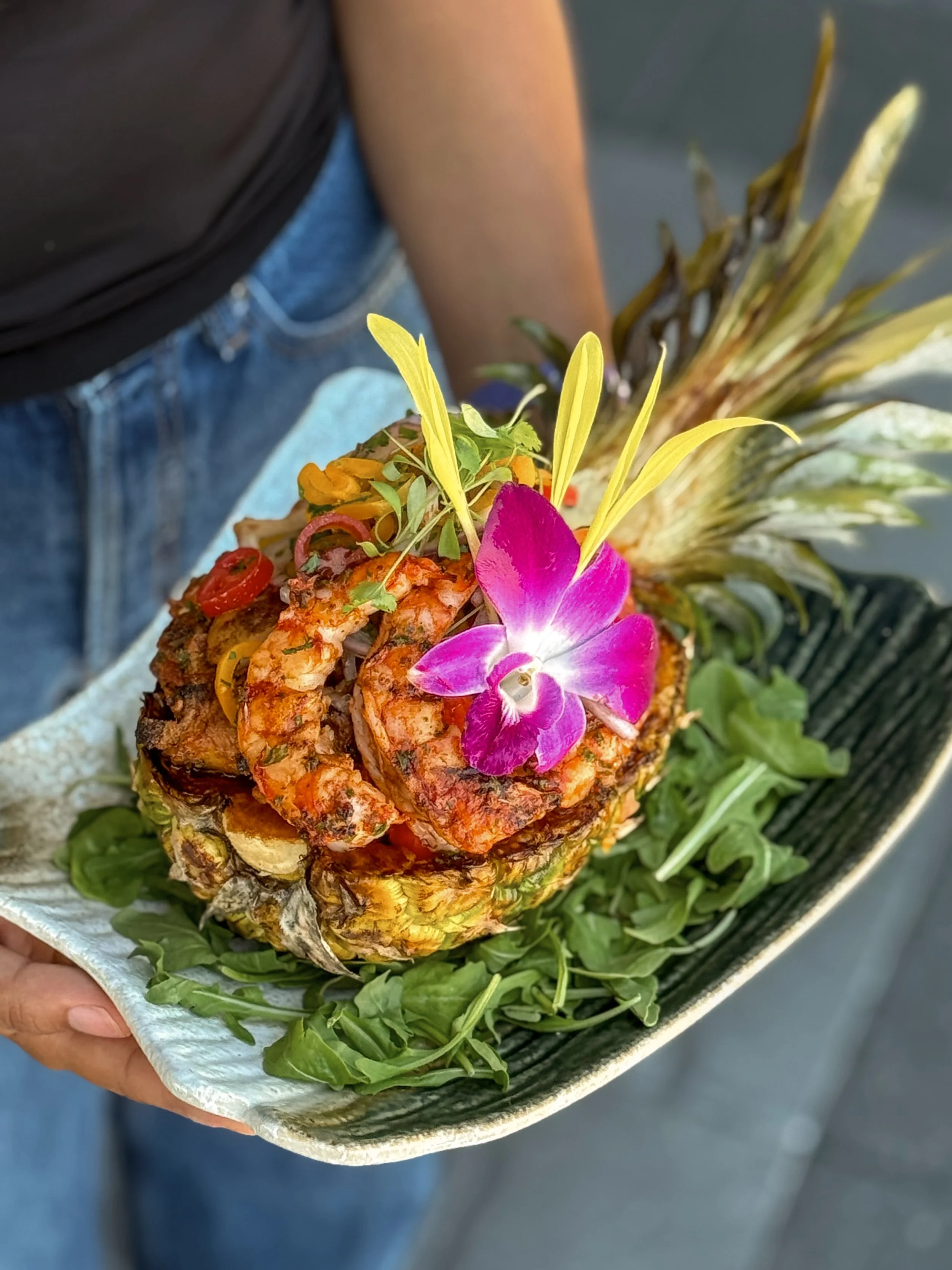 Pineapple Chapa Rice served in a halved pineapple with Argentinian red shrimp and an orchid garnish