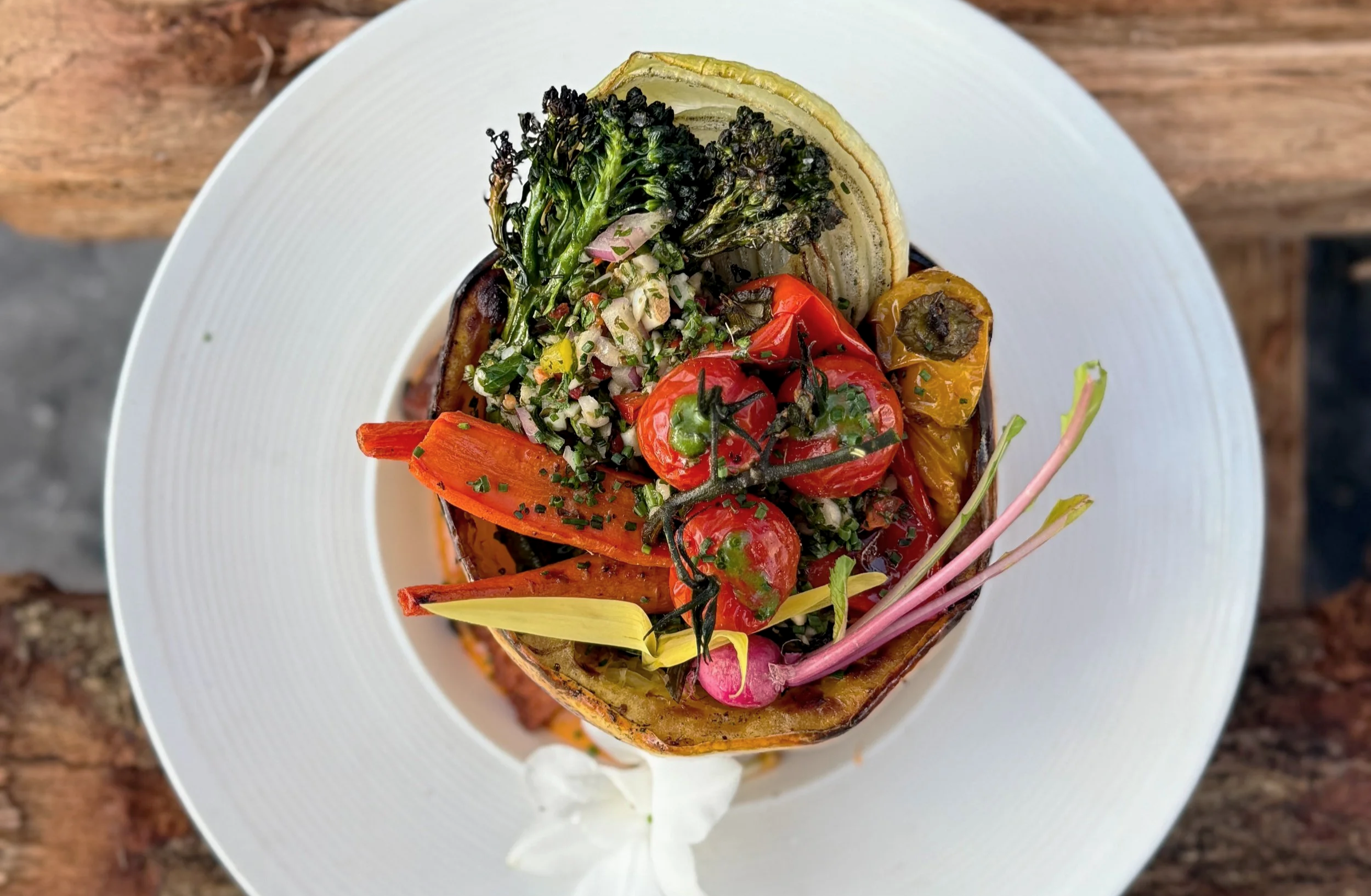 Plated ember-roasted spaghetti squash with parrilla-grilled vegetables plated over a grill at Asado Life.