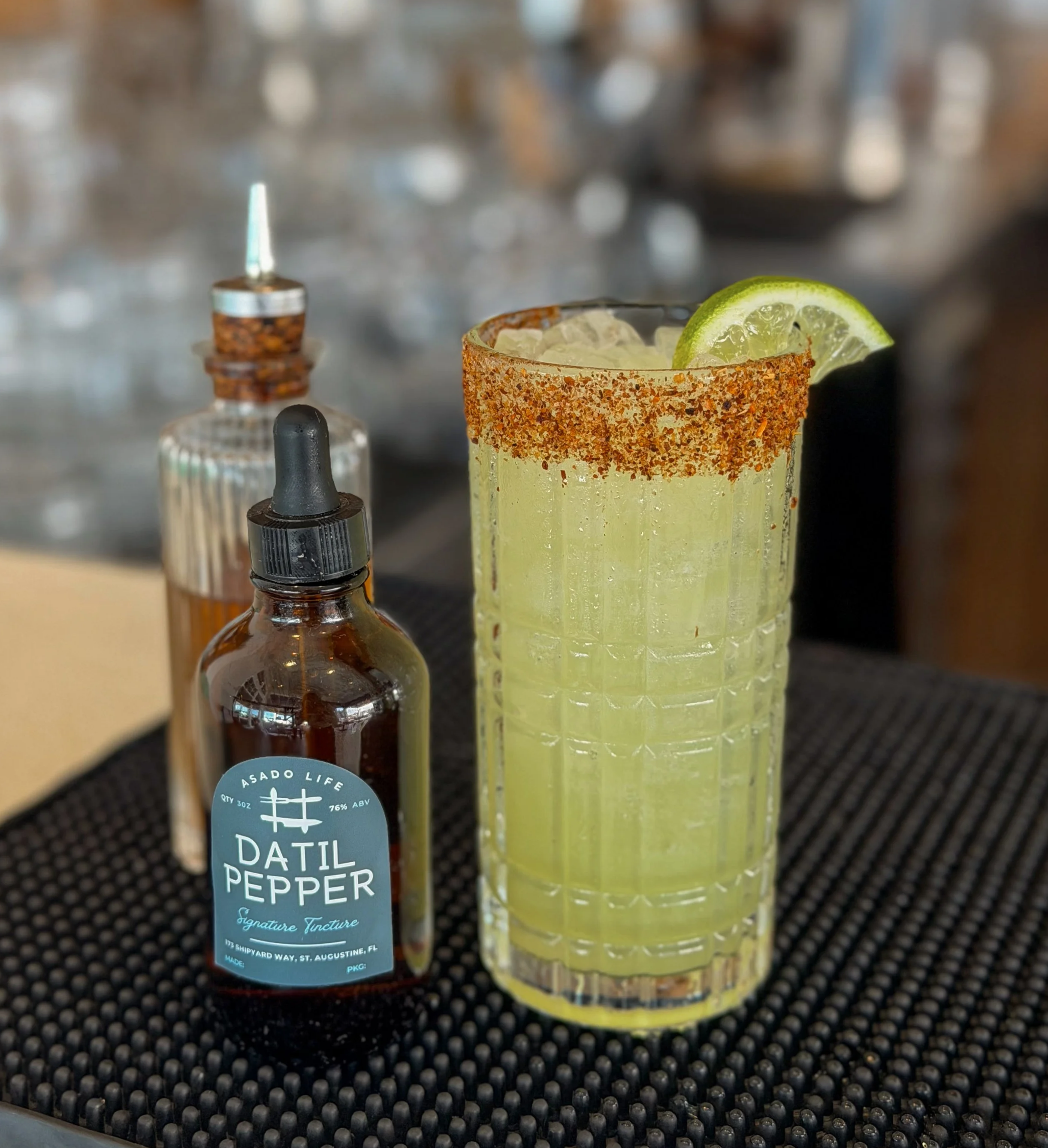 Asado Life’s housemade datil pepper tincture alongside a craft cocktail, adding a bright, spicy kick to the glass.