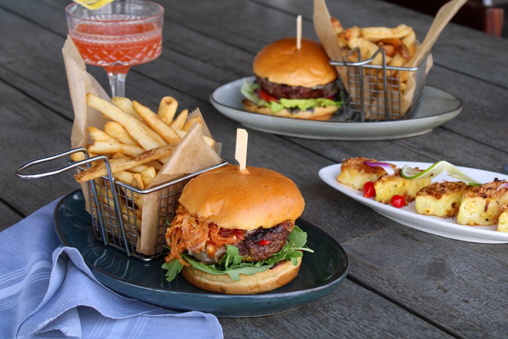 Gaucho and Americano Burgers plated on a table with the Roasted Pineapple Appetizer