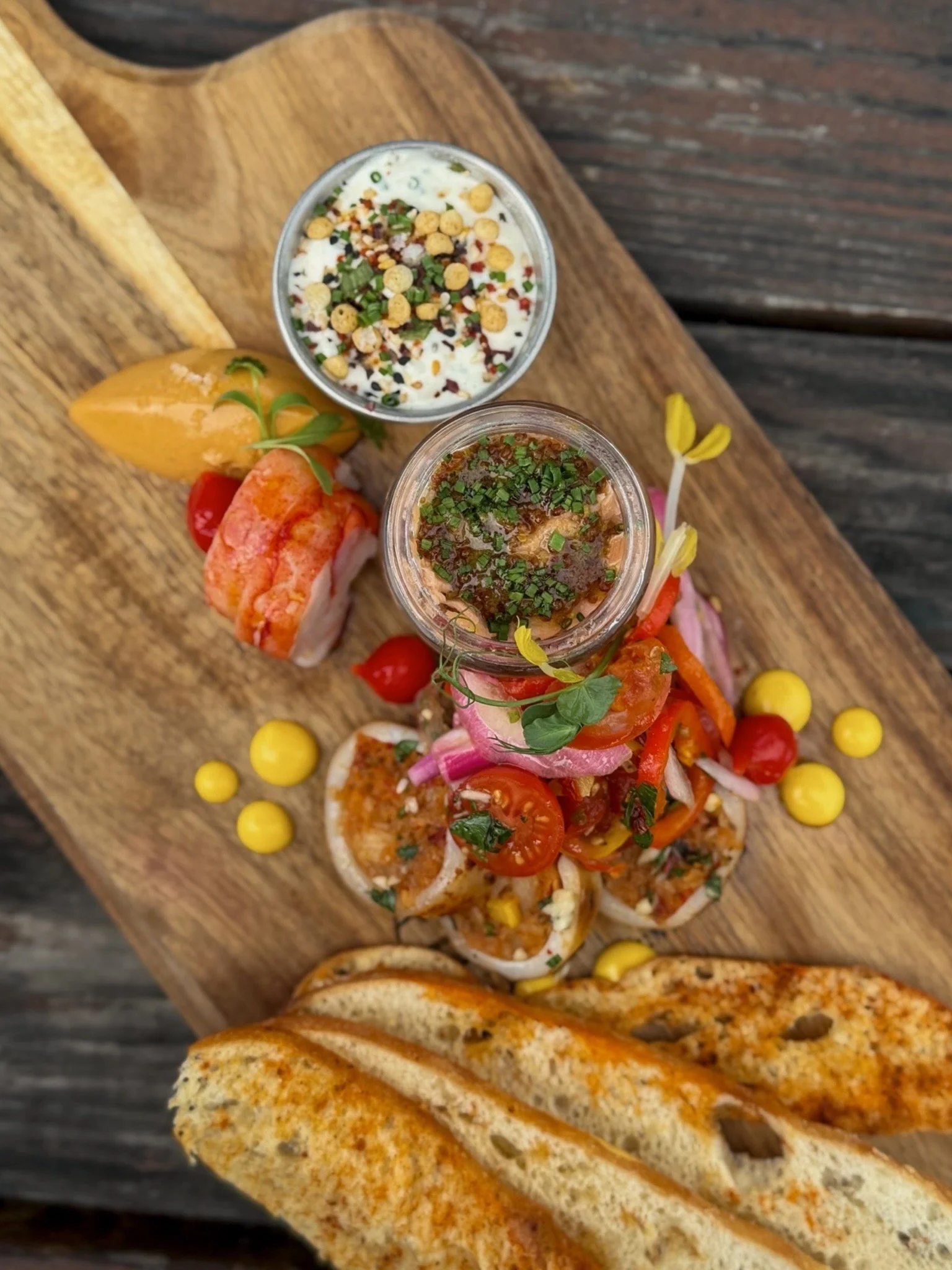 Top down view of a Seacuterie board featuring house-made seafood specialties, sauces, spreads, and crisp crostini, served at Asado Life.