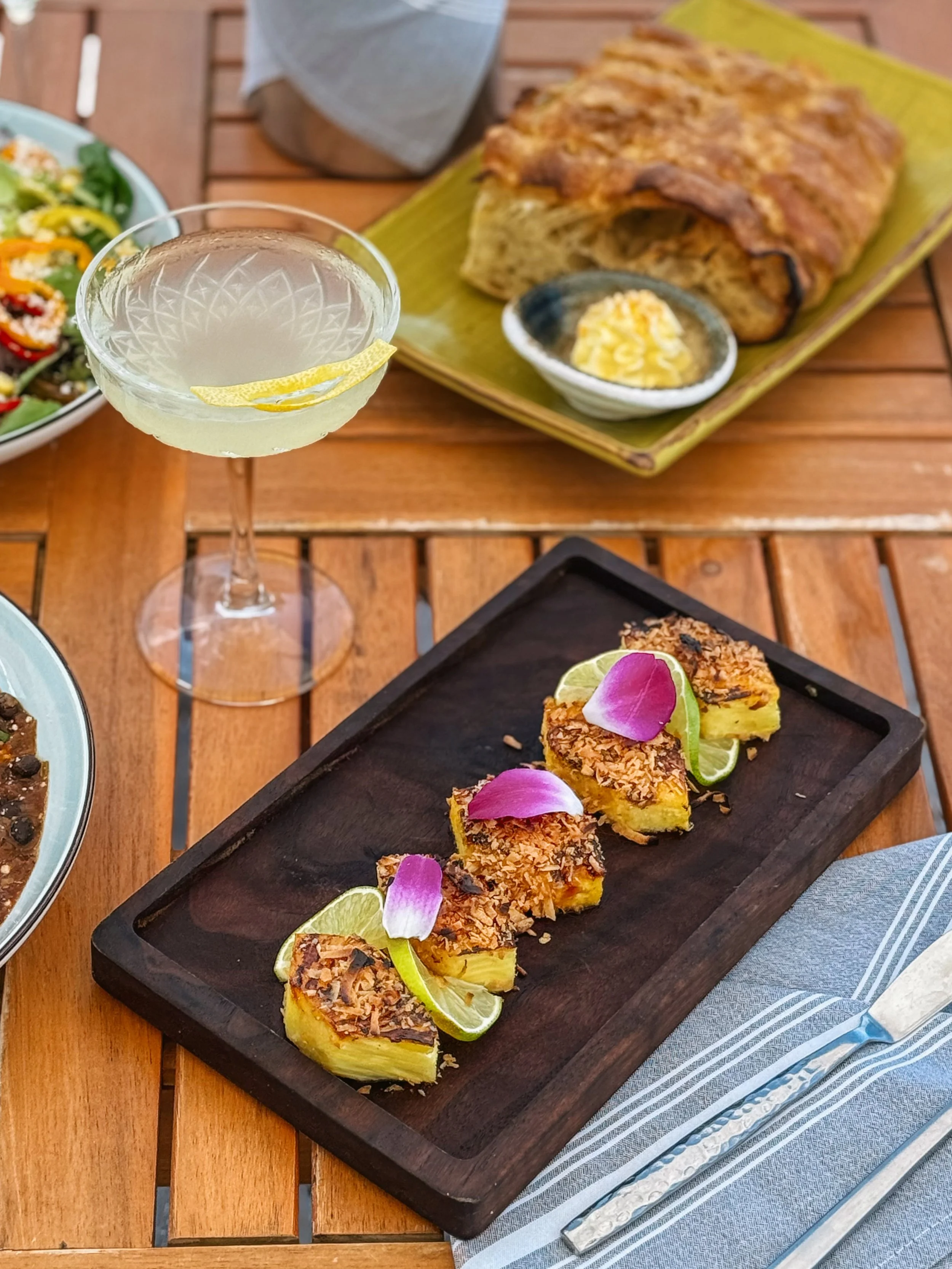 Roasted Pineapple Appetizer on a plate next to a yellow cocktail