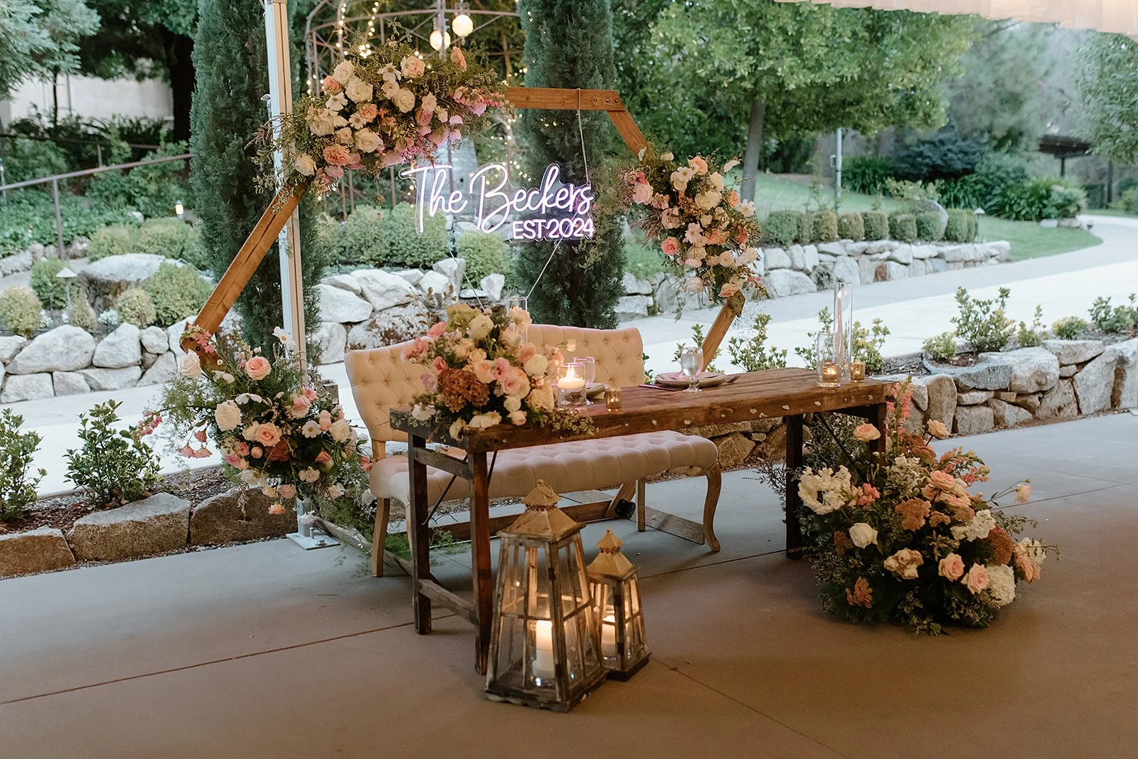 rustic sweetheart table with neon sign and floral arch