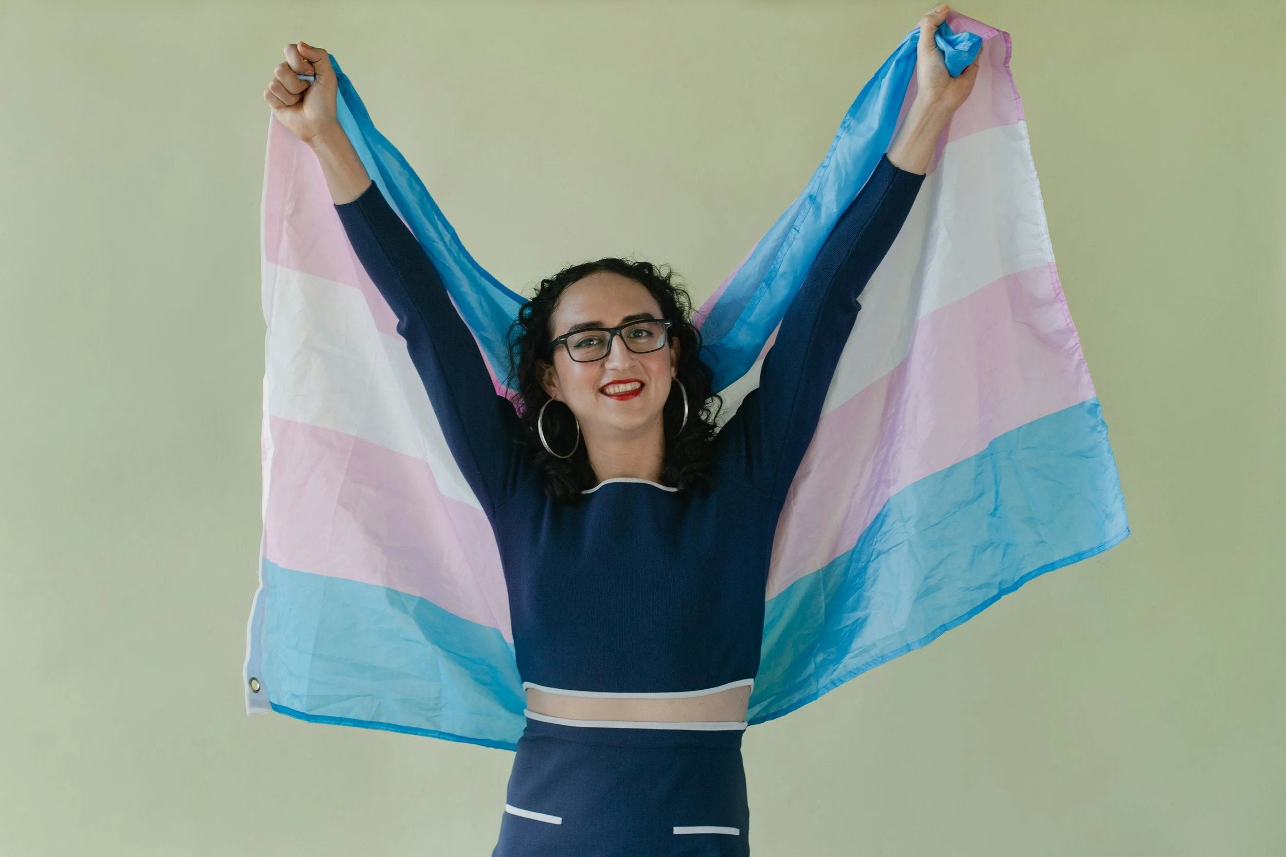 trans person holding a trans flag in section about gender-affirming care in banff and canmore