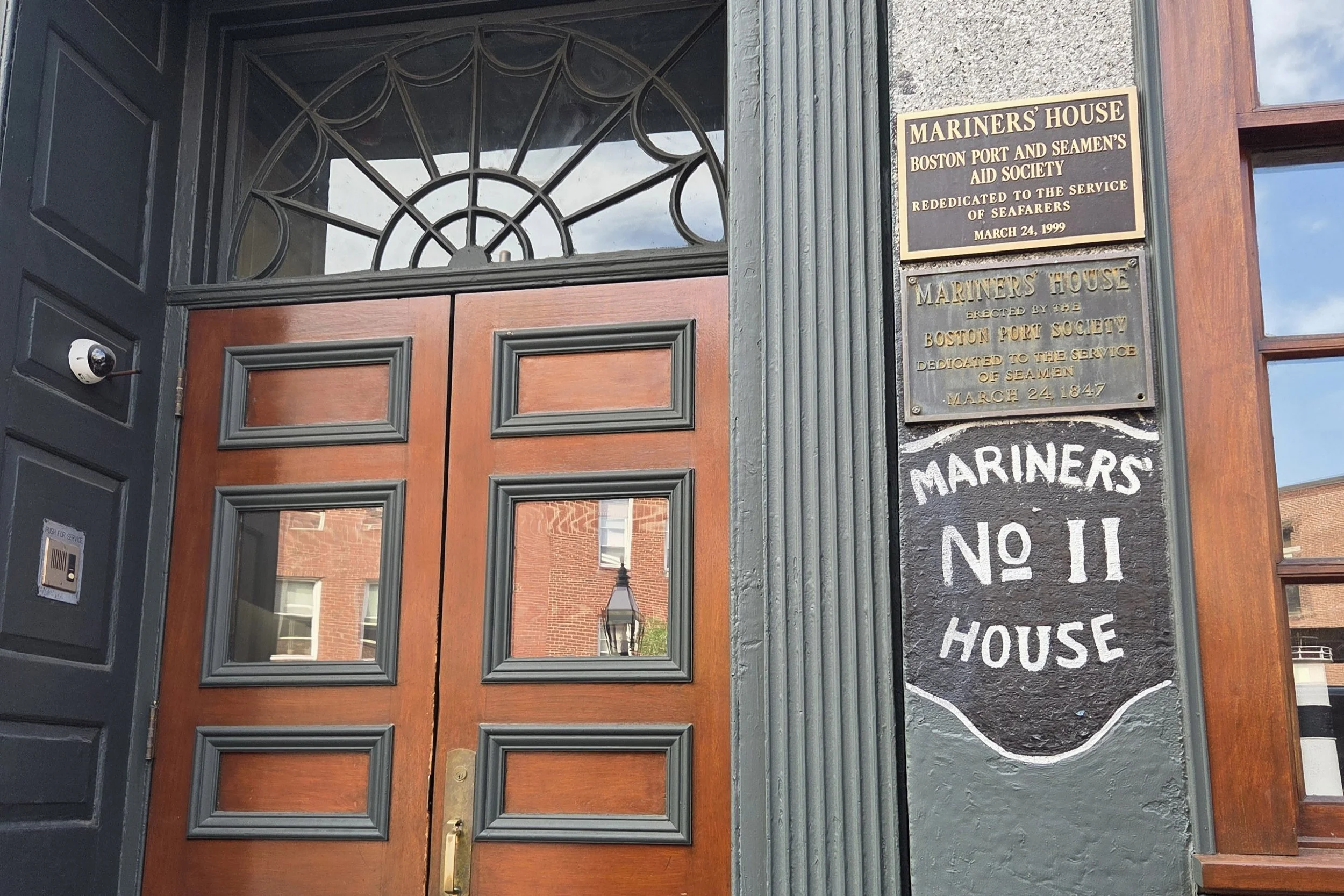 wooden double door with green detailing. Front façade of the Mariner's House