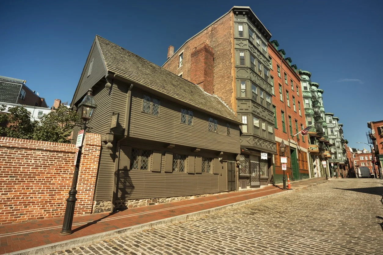 1600's wooden brown house in a city square with brick buildings and cobblestone streets