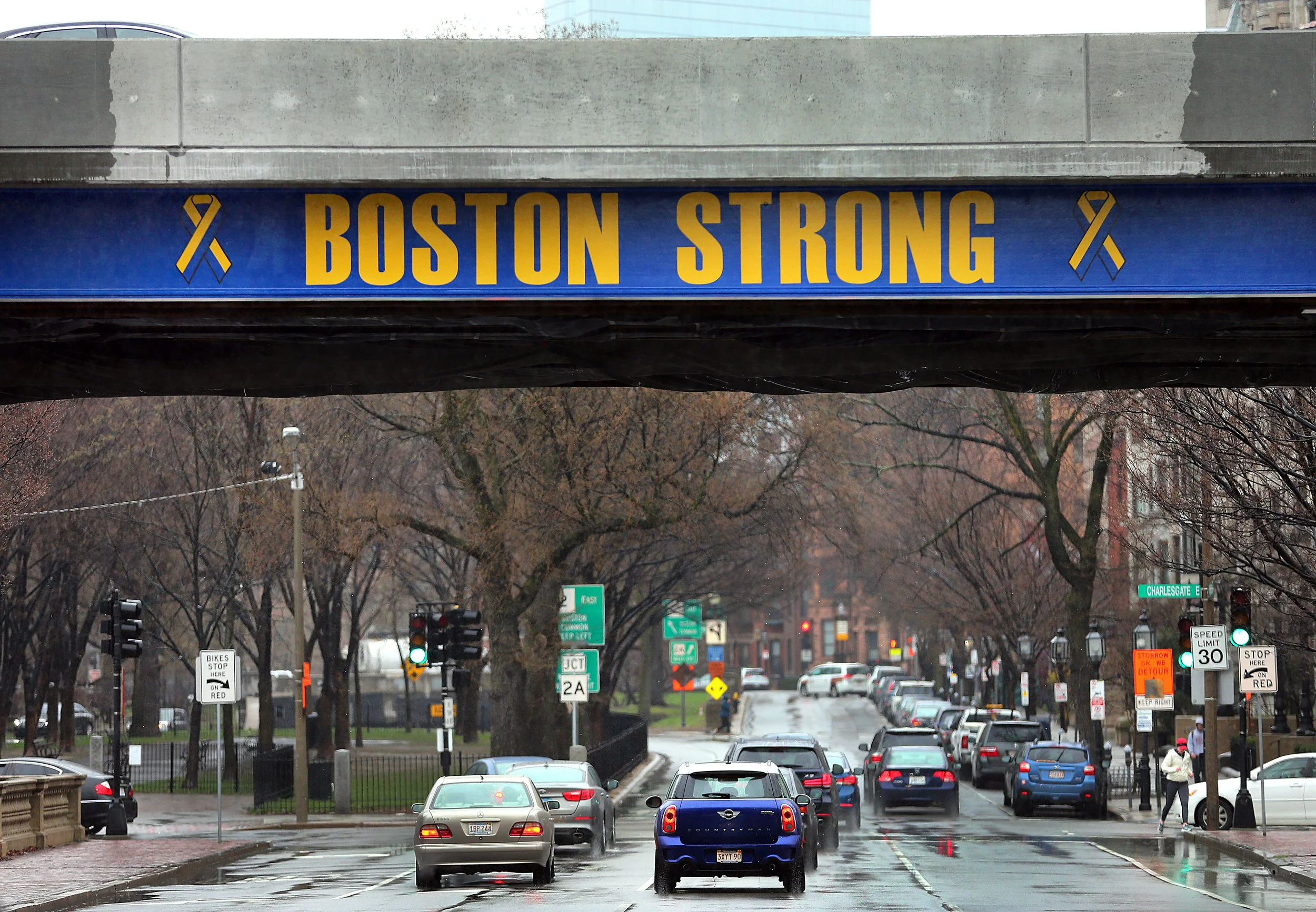 concrete car overpass with the navy blue background and golden yellow words "Boston Strong" above Commonwealth Avenue.