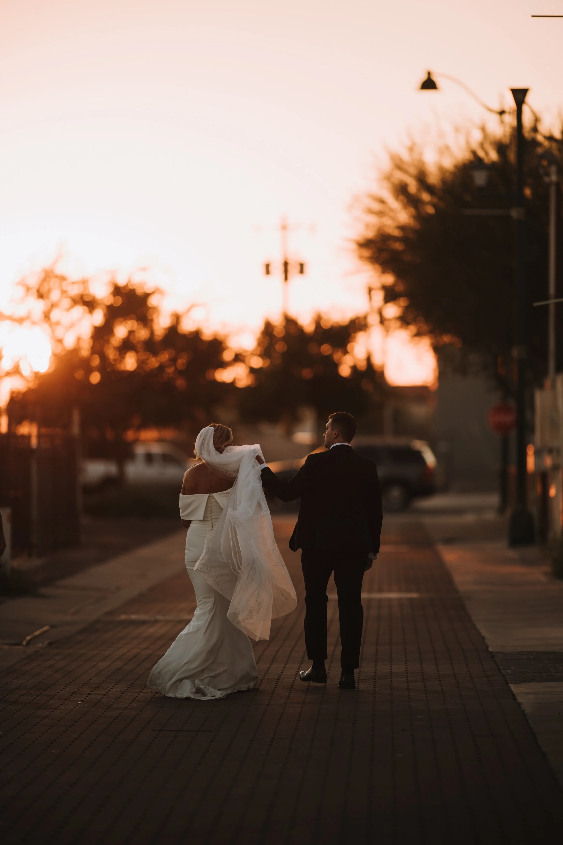 Candid photo of groom holding bride's dress at wedding. Tre Bella. Mesa, Arizona. Canon R5.