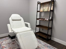 White reclining chair in a room with a dark wooden bookshelf and a patterned rug.