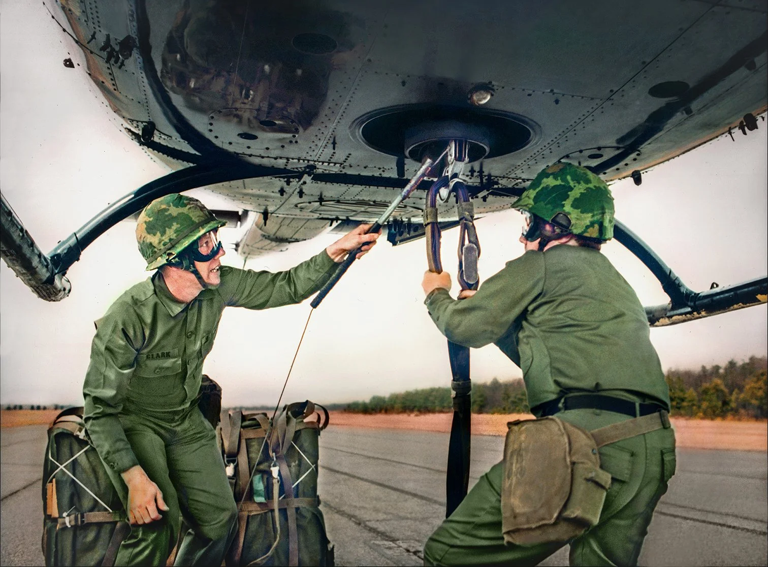 US Army Riggers training hooking up cargo to hovering helicopter  -  US Army helicopter training base  -  Fort Lee, Virginia  1980  -  client: US Army