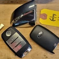 Photo of two car key fobs on a wooden surface with JC Lock & Key tag attached.