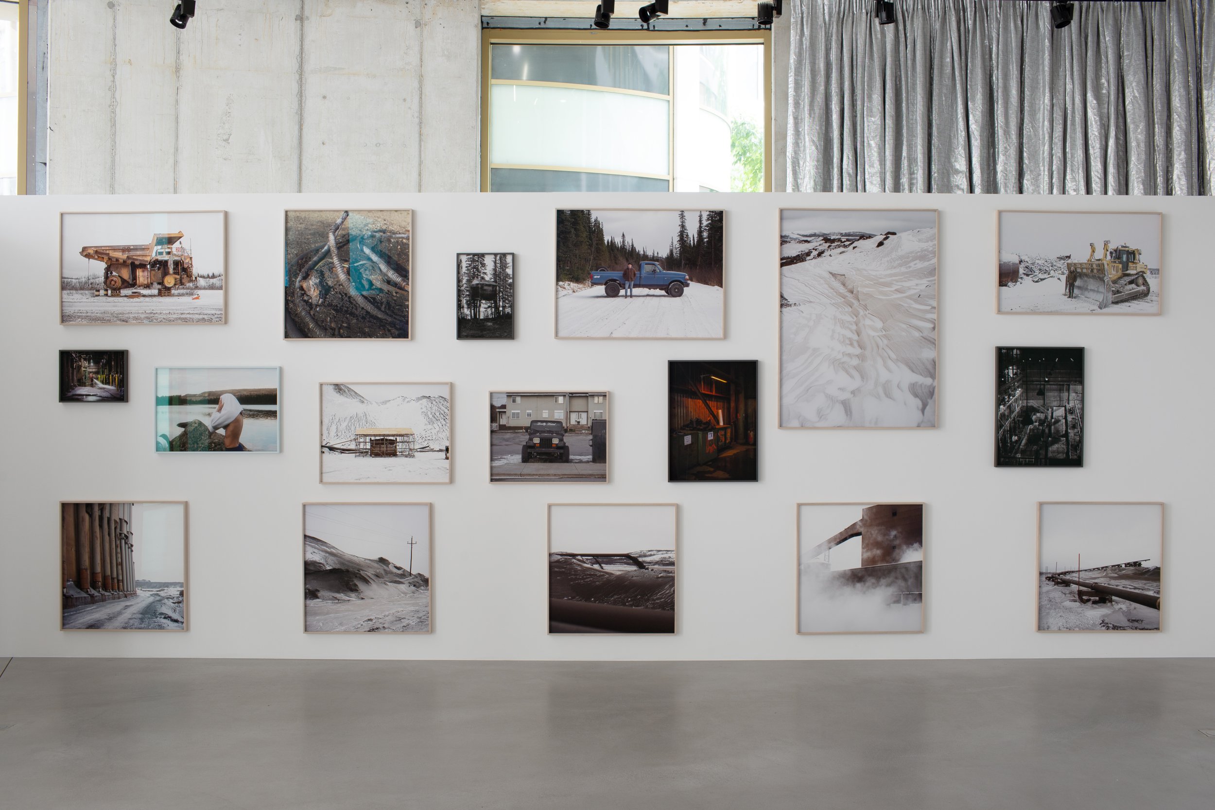 Art gallery wall displaying framed photographs of industrial scenes, machinery, and landscapes.