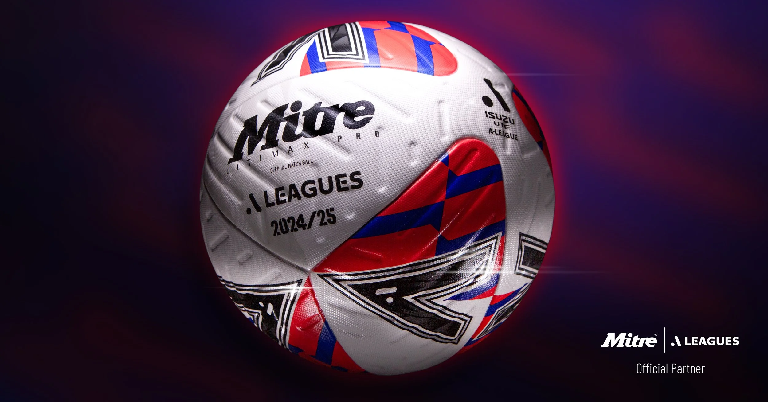 Close-up of a soccer ball with red, white, blue, and black patterns, branded with Mitre and displaying league information, set against a dark background.