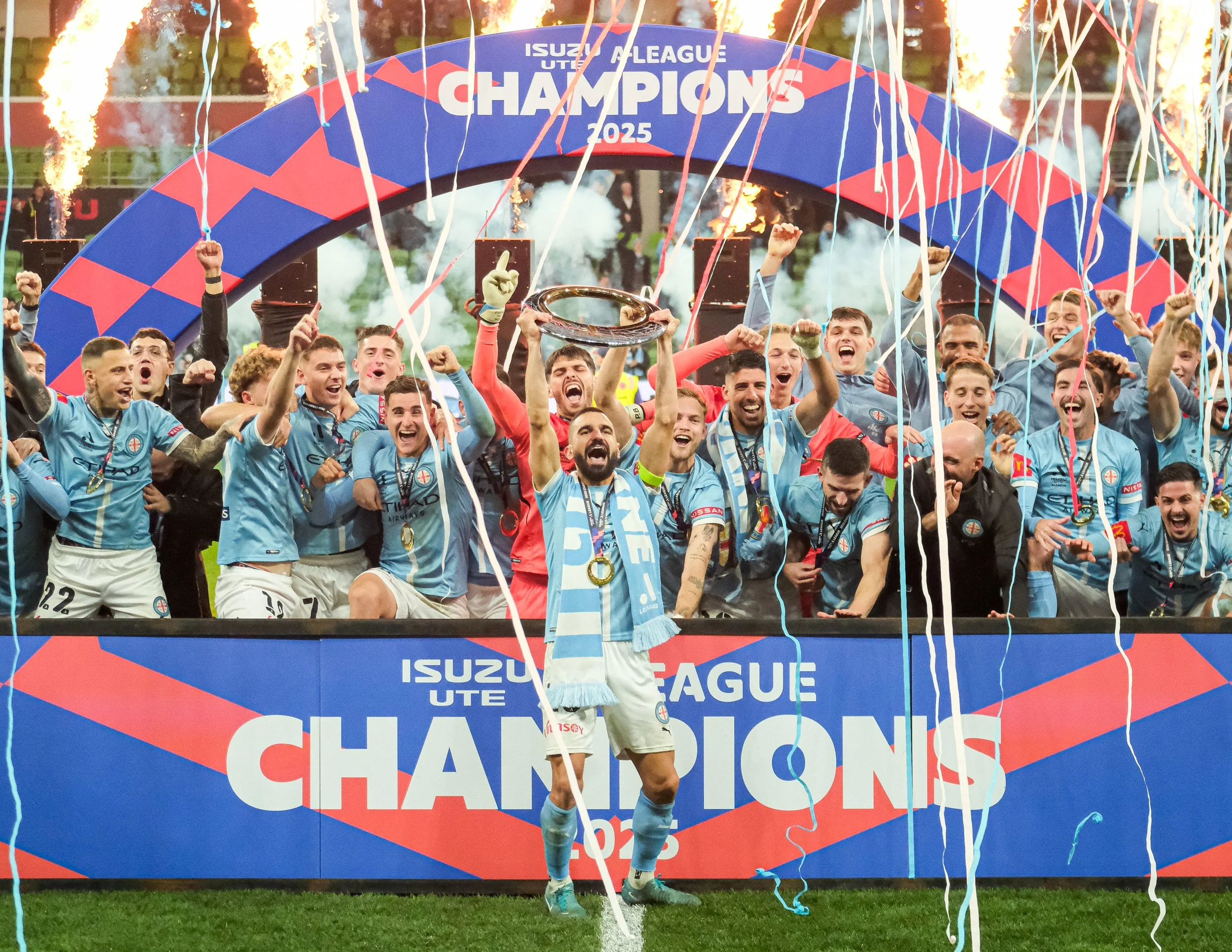 Celebrating soccer team on podium after winning championship, surrounded by streamers and fire effects.