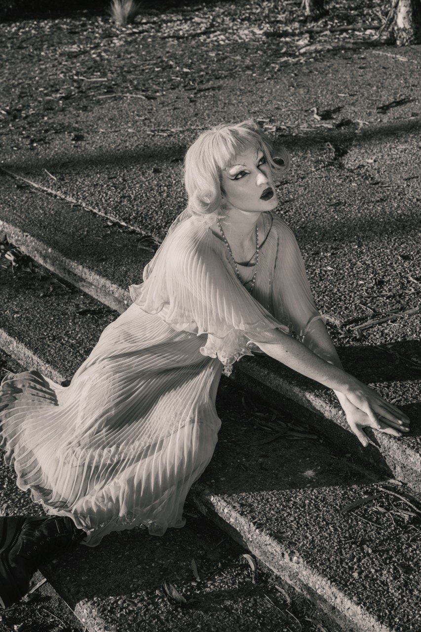 Woman in a flowing dress sitting on outdoor steps in a black and white photo.