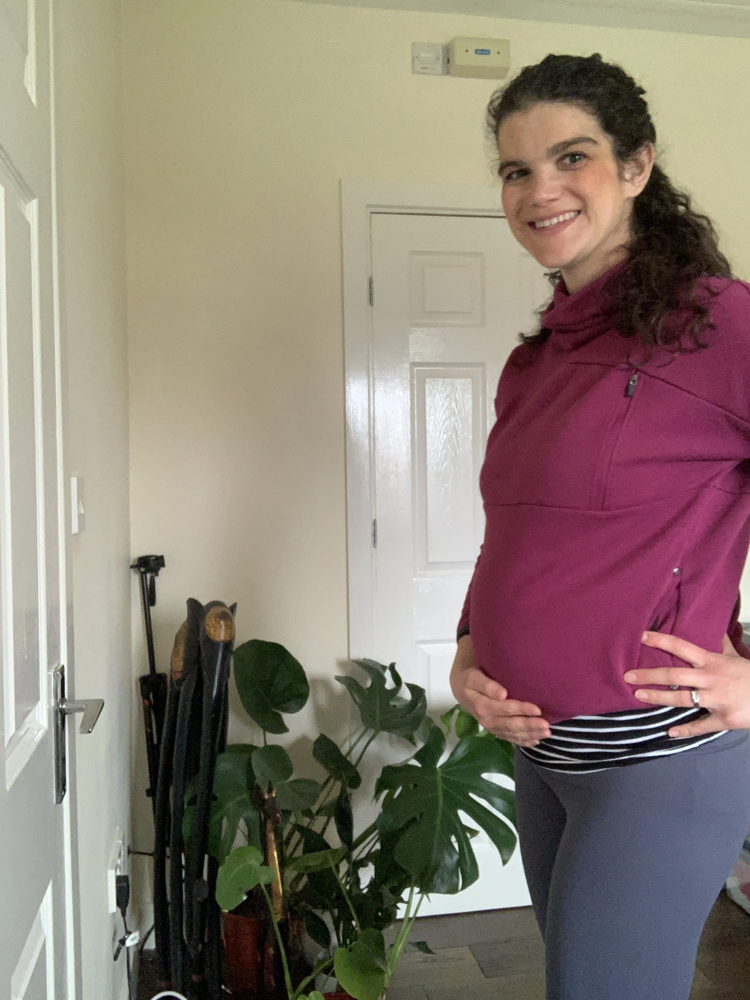 Mother in second pregnancy holding her 20 week bump about to teach a pregnancy yoga class online