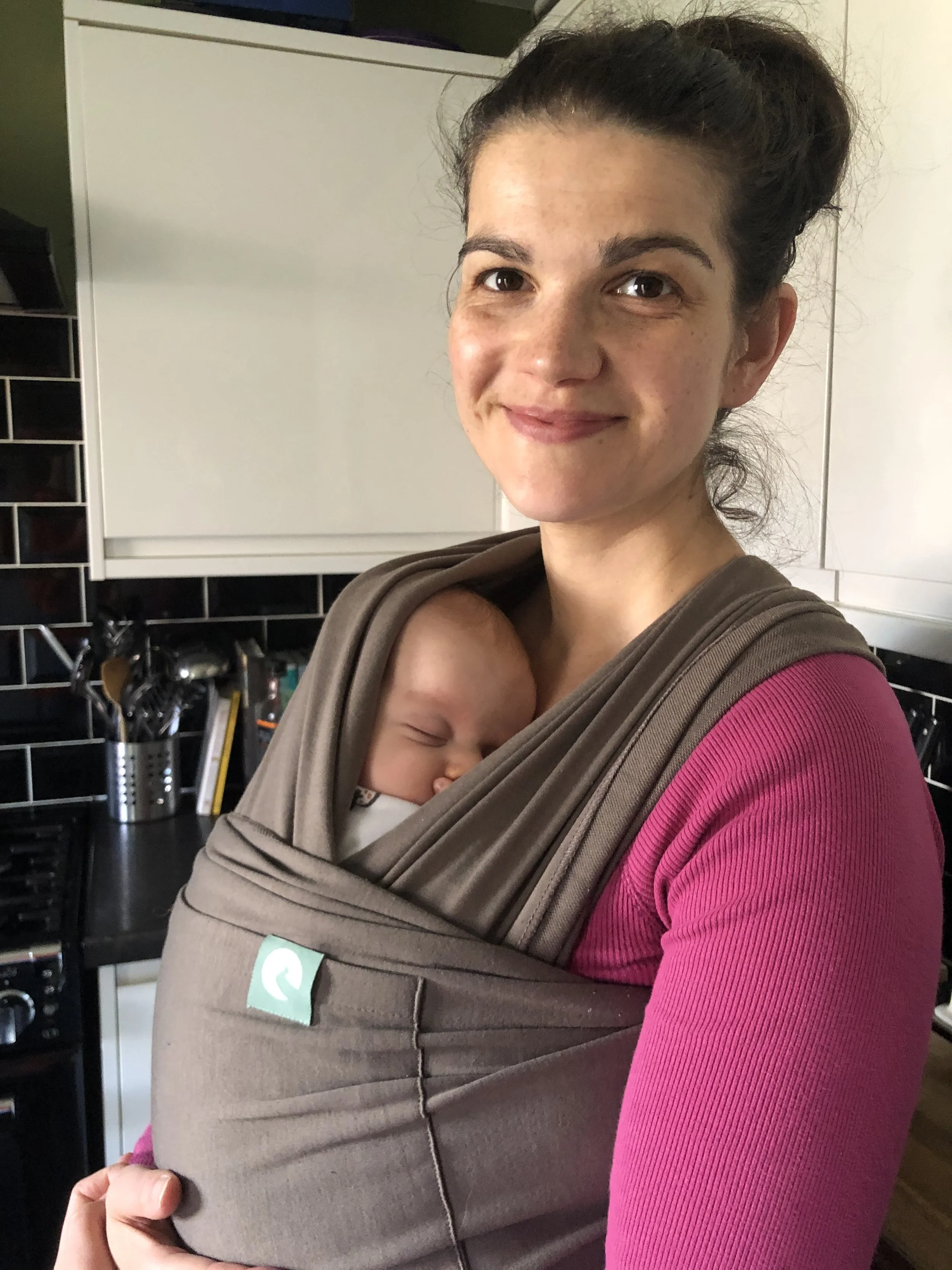 Tired Mother holding baby in need of a postnatal massage