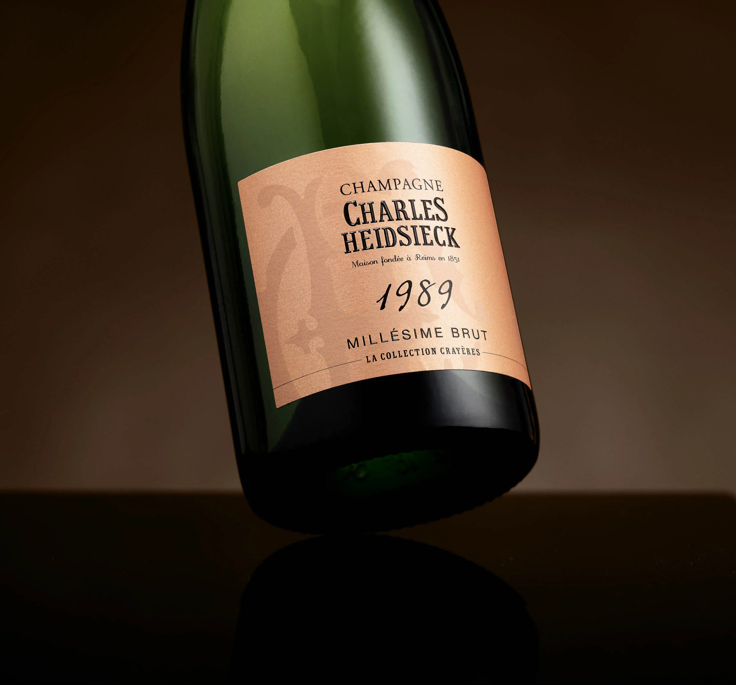 A tilted green bottle of Charles Heidsieck champagne with a pink label reading 1989 Millésime Brut.