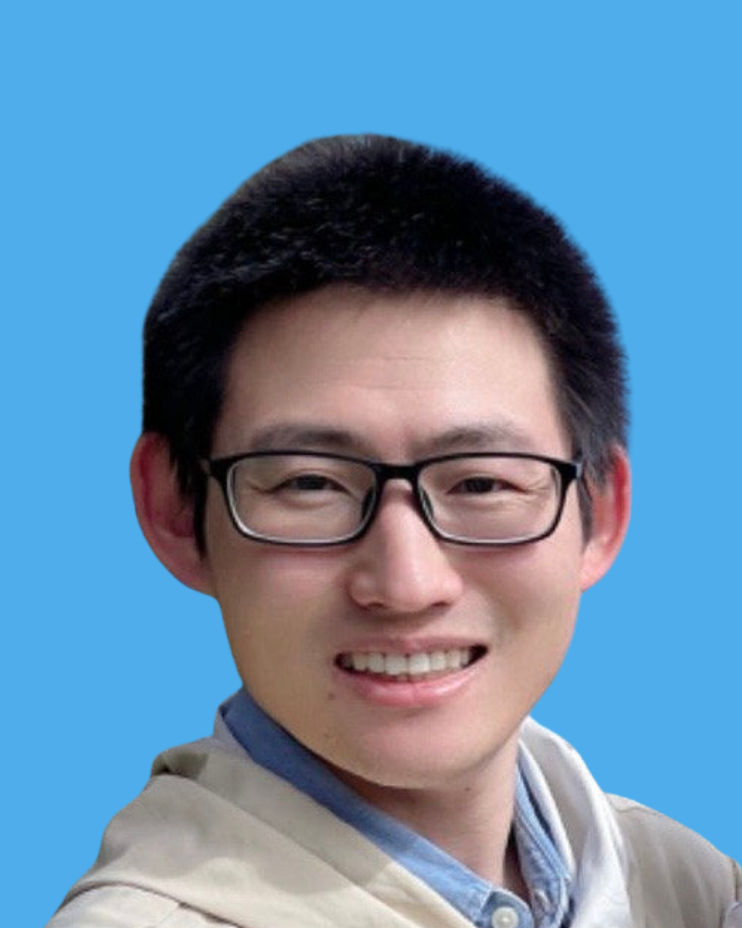 Close-up of a smiling young man with glasses, short black hair, wearing a beige jacket and light blue shirt, set against a solid light blue background.