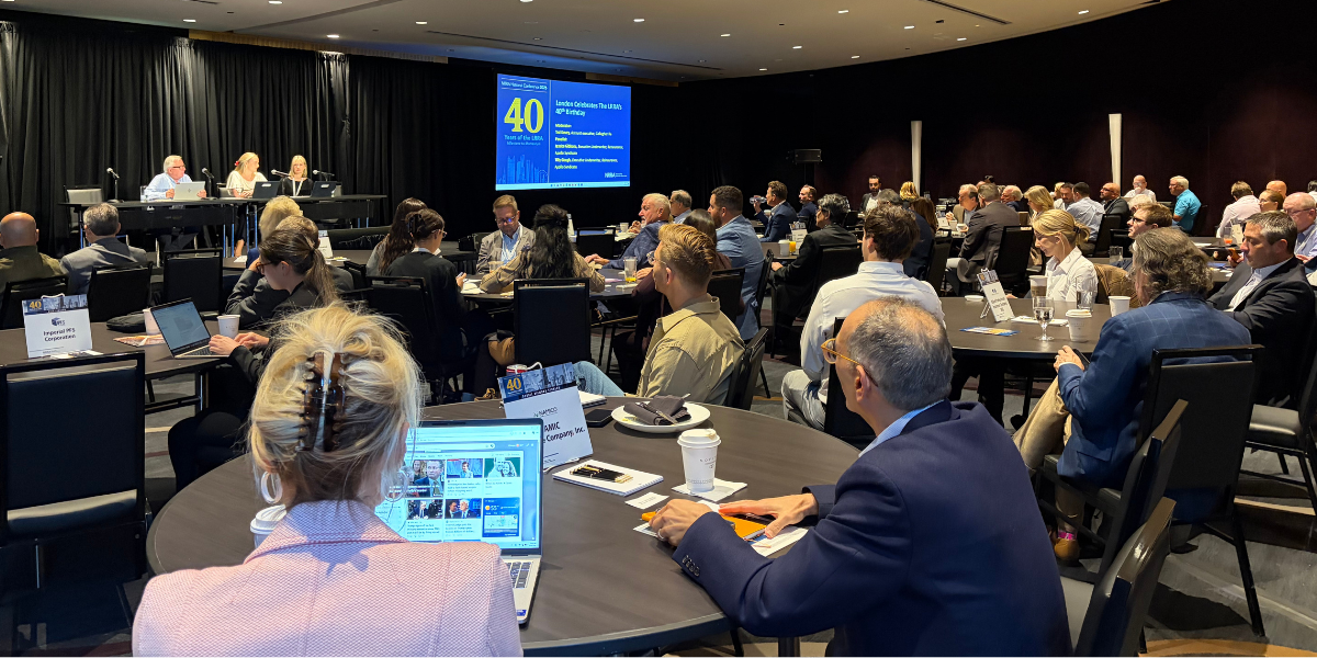 Wide shot of the conference room with the London Reinsurers panel on stage and professionals listening from round tables around the room.