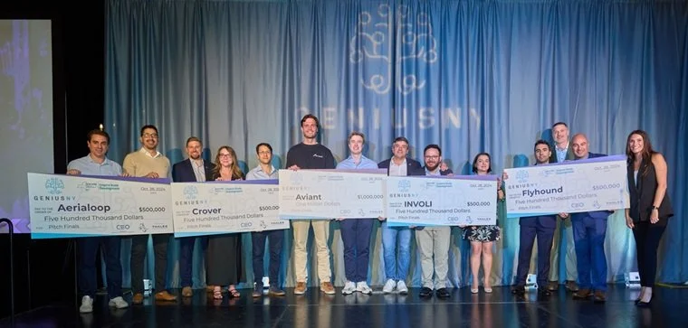 Image of GeniusNY teams holding checks, in reference to Think Variant partnering with GeniusNY