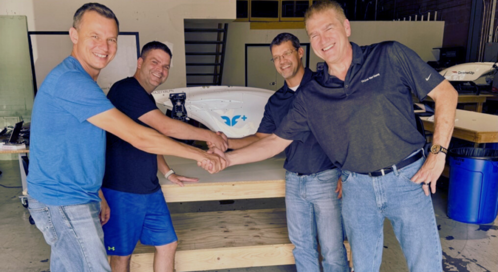 Photo of Blueflite founders shaking hands with Think Variant co-founders Scott Antonacci and Harold Watkins during their new drone manufacturing partnership.