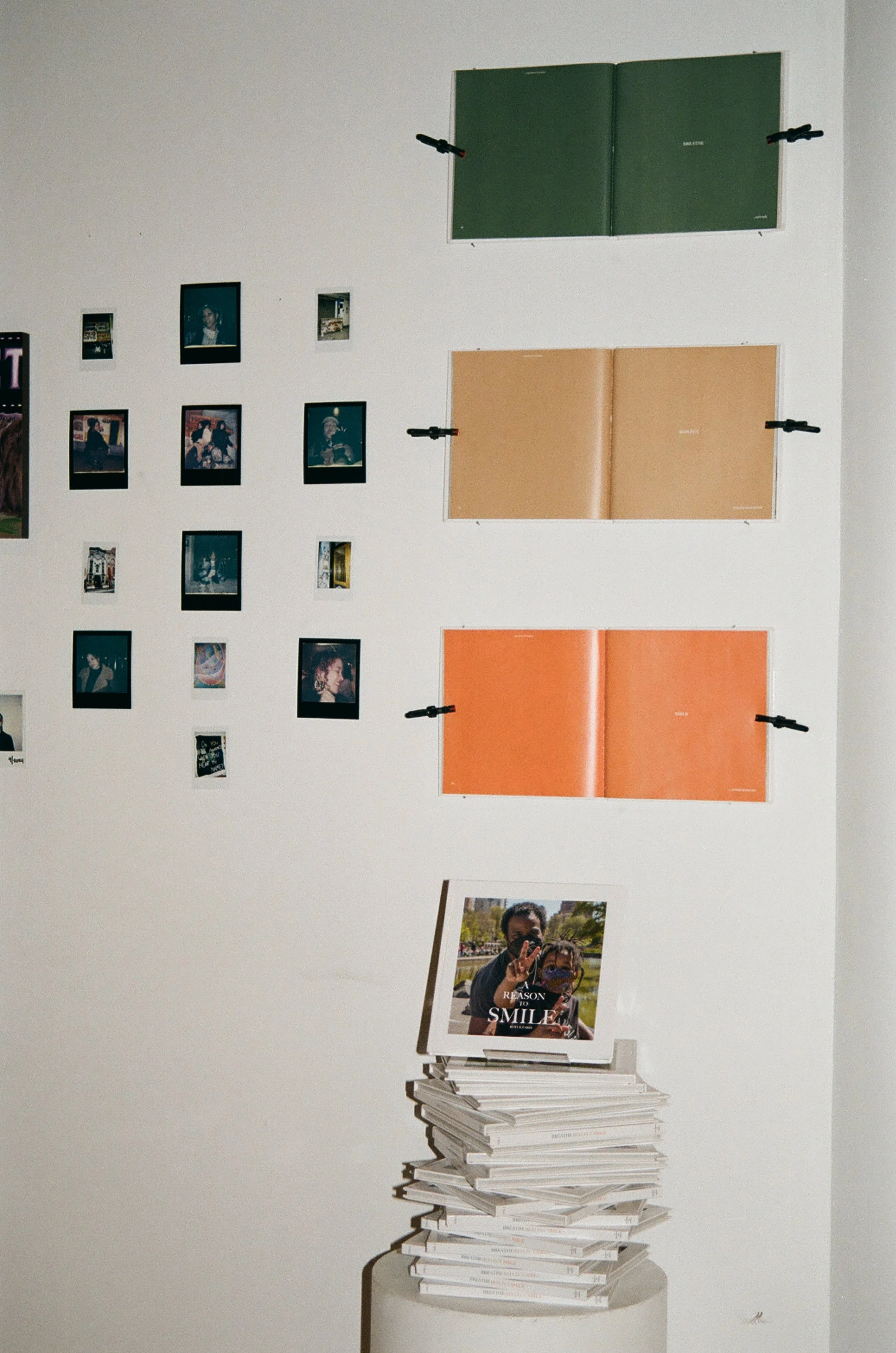 Royce Paris's photography book titled "A Reason to Smile" next to polaroids by Strawberry