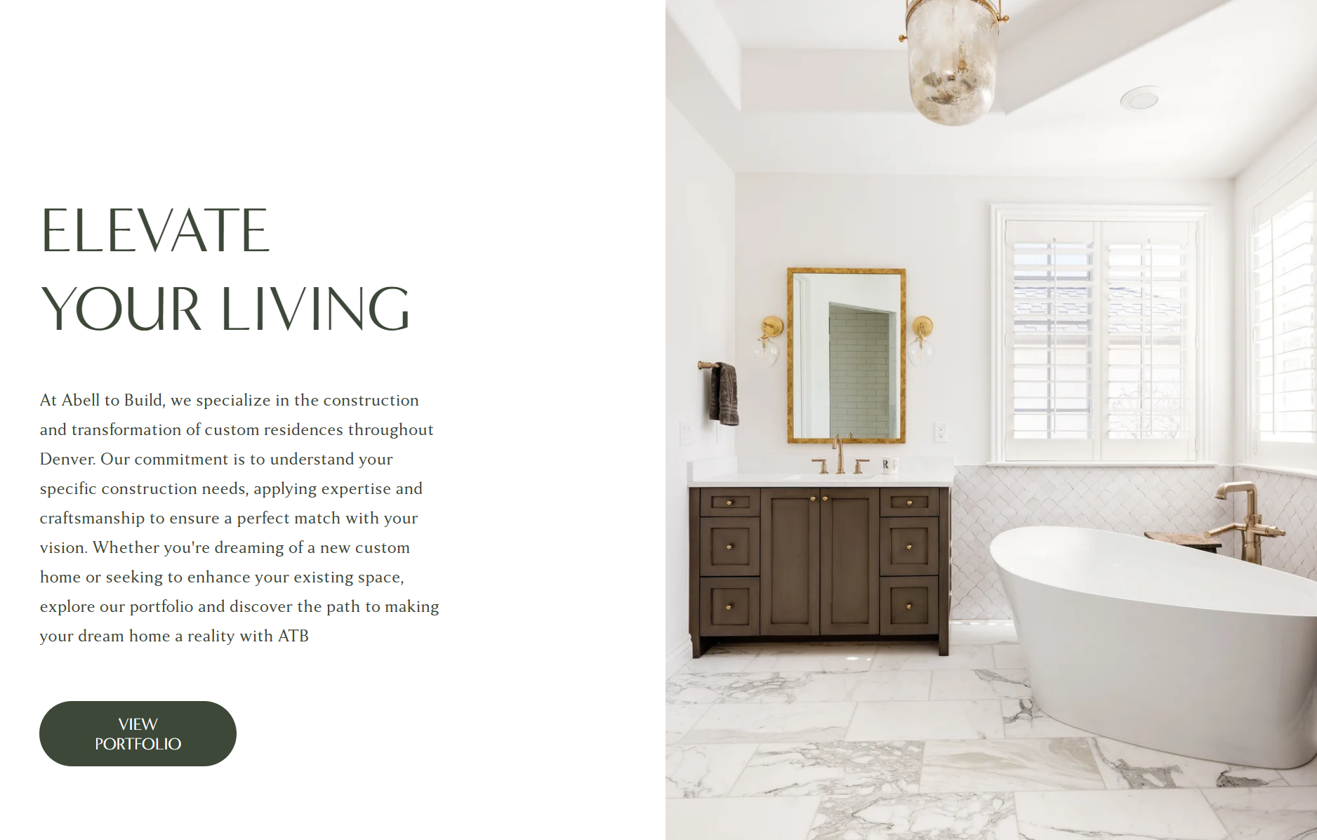 A bathroom with white walls, a large window with white shutters, a marble floor, a dark wood vanity with a mirror and gold fixtures, and a free-standing bathtub with gold fixtures.