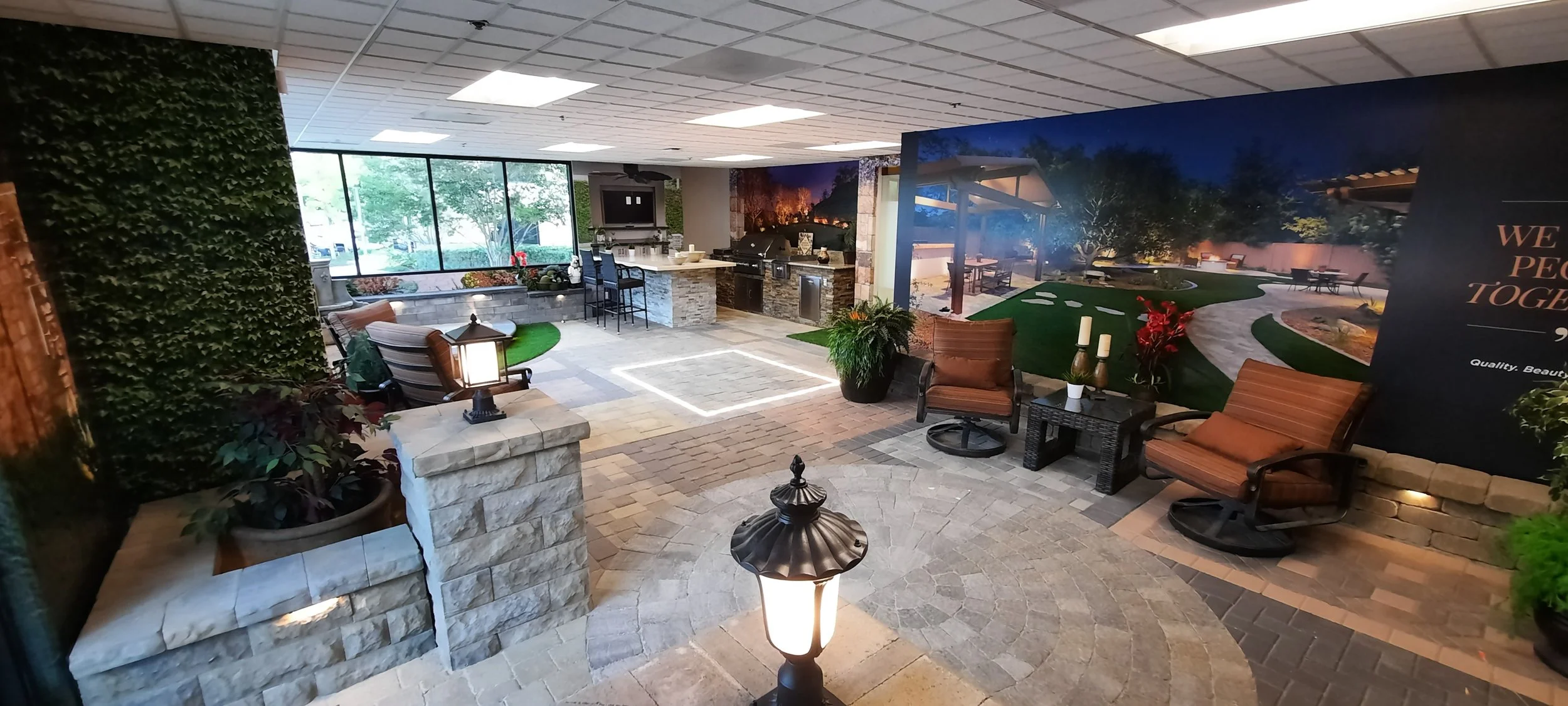 Indoor patio with chairs, potted plants, and a mural of an outdoor scene with trees and pathway.