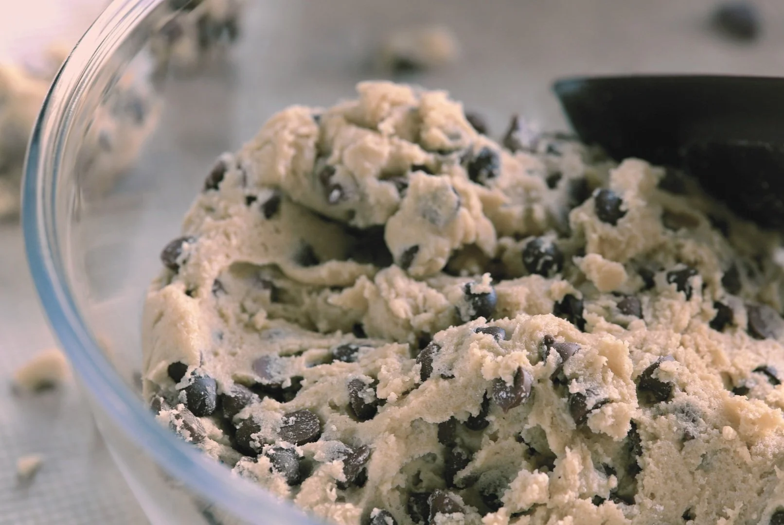Chocolate chip cookie dough batter in a glass bowl