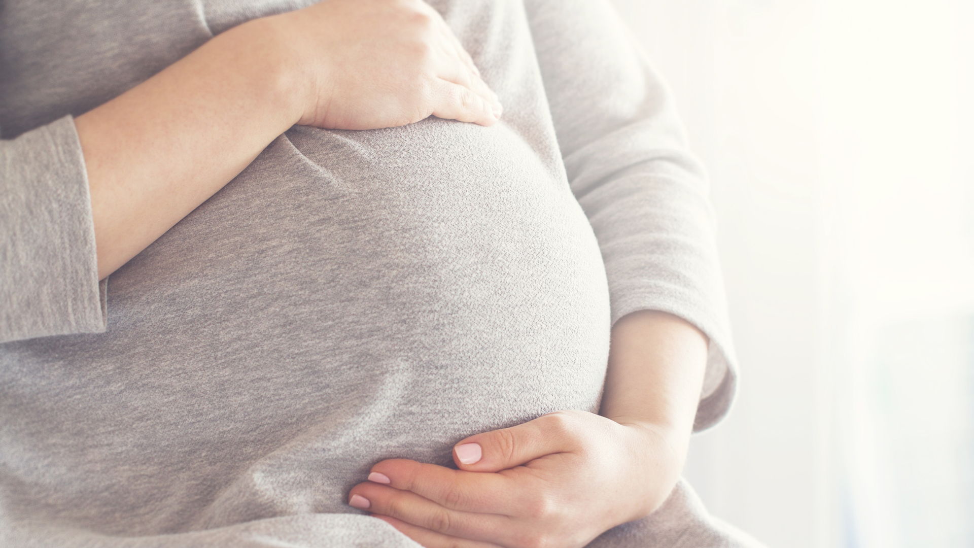Two hands cradling a pregnant belly