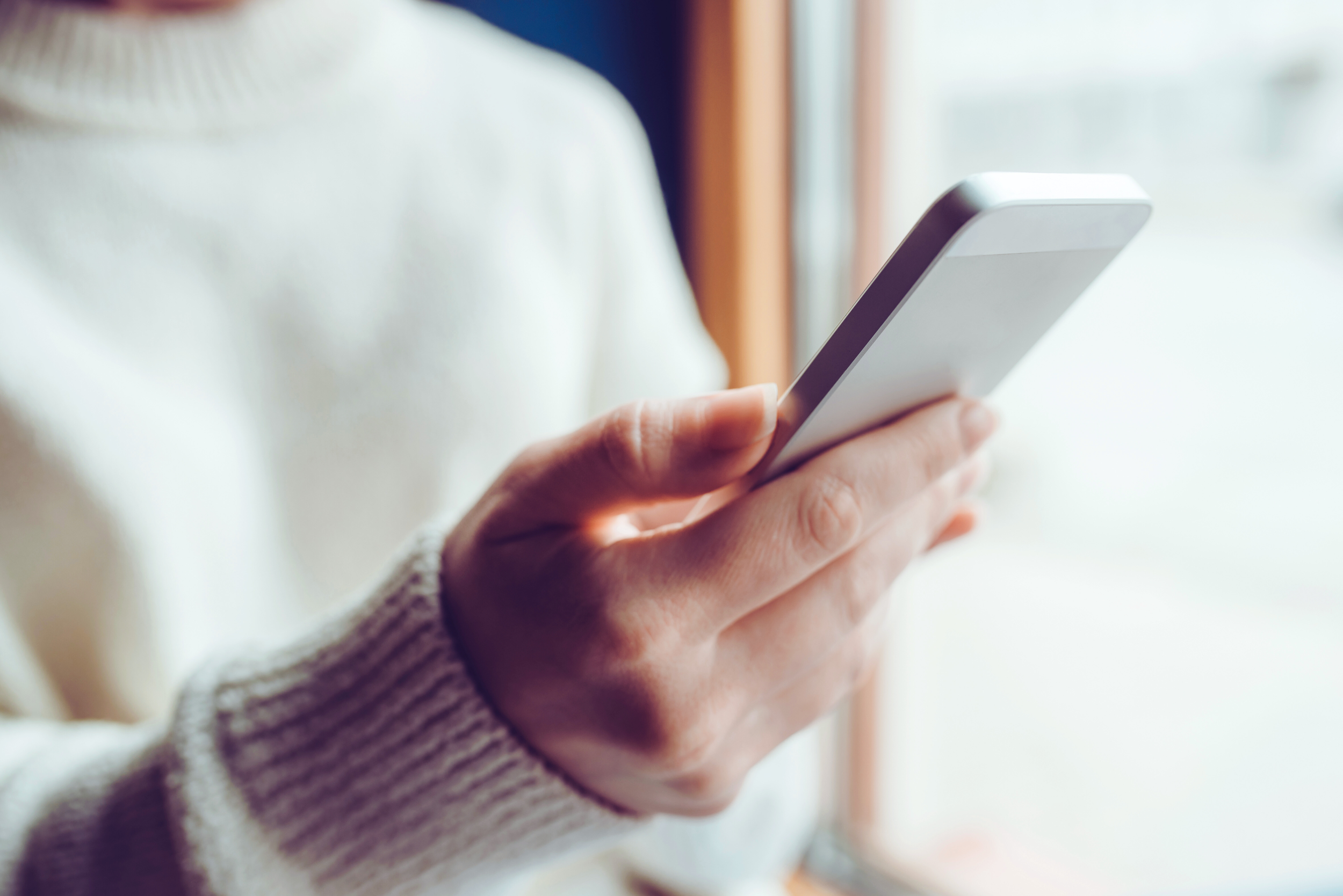 A hand holding a silver smartphone.