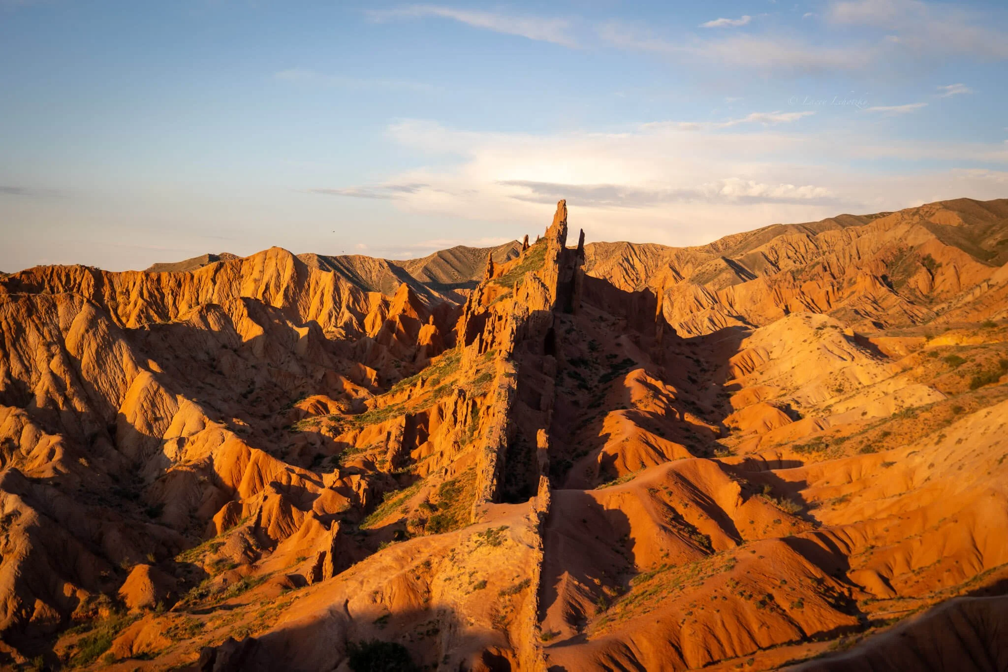 a red rock formation that looks like a castle spears from the surrounding landscape, the sunset making it glow, fairytale canyon kyrgyzstan