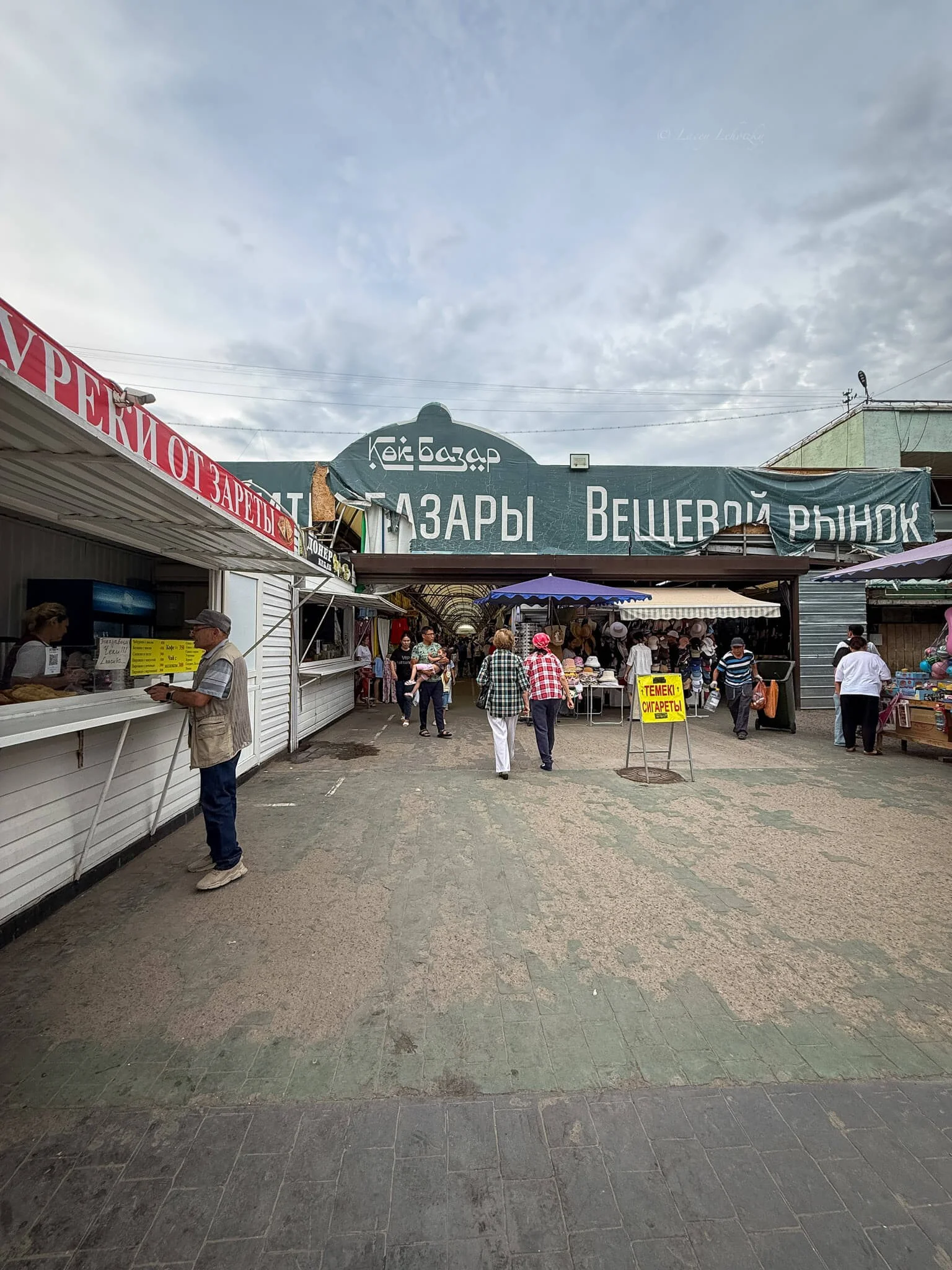 front entrance of green bazaar in almaty kazakhstan with people coming and going from stalls selling wares
