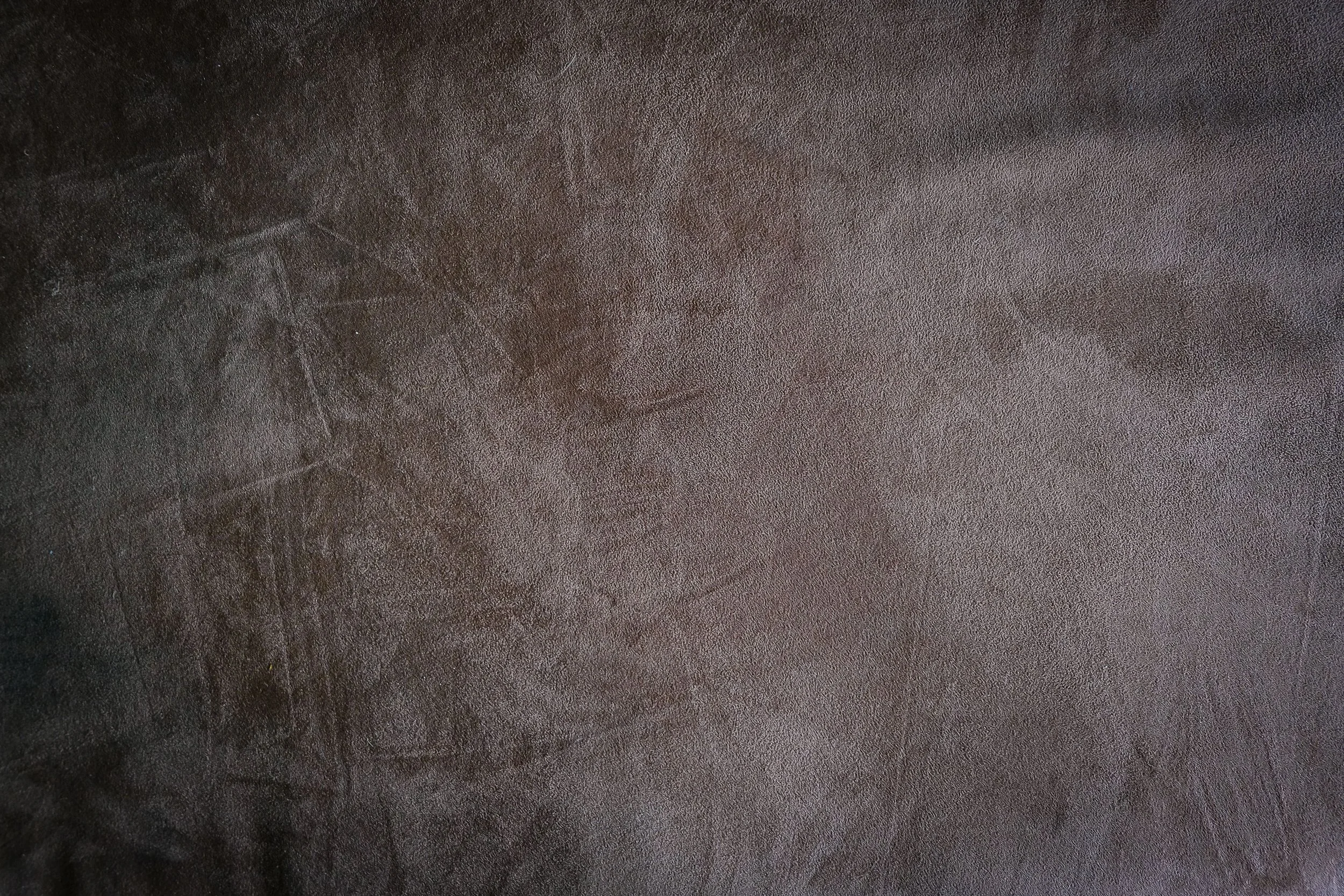 Close-up of a dark brown leather surface with visible texture and stitching.
