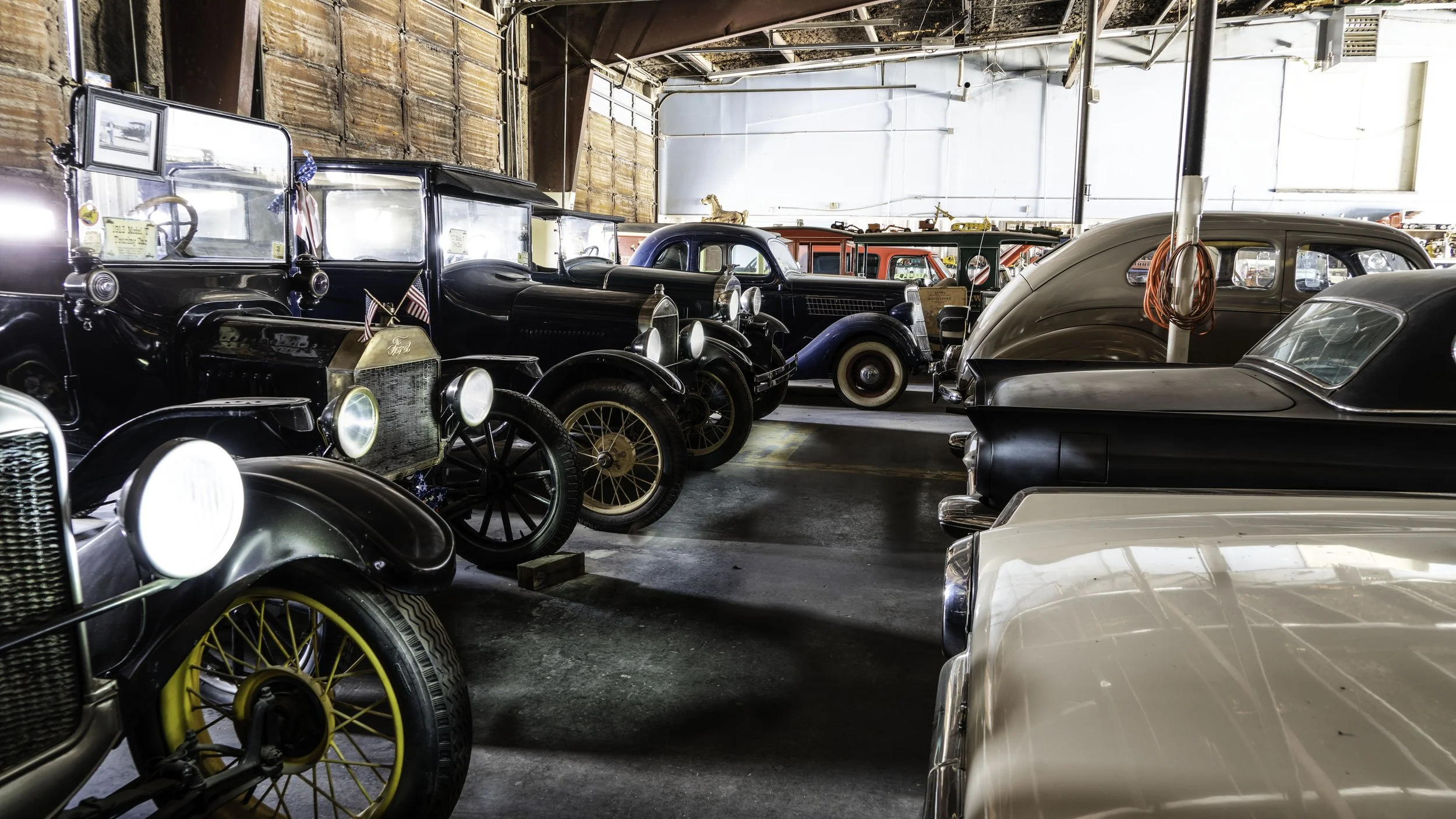 Limited edition fine art photograph by Jason Sponseller, featuring a collection of vintage automobiles inside a historic garage in Moriarty, New Mexico, with classic car details, aged textures, and nostalgic American atmosphere