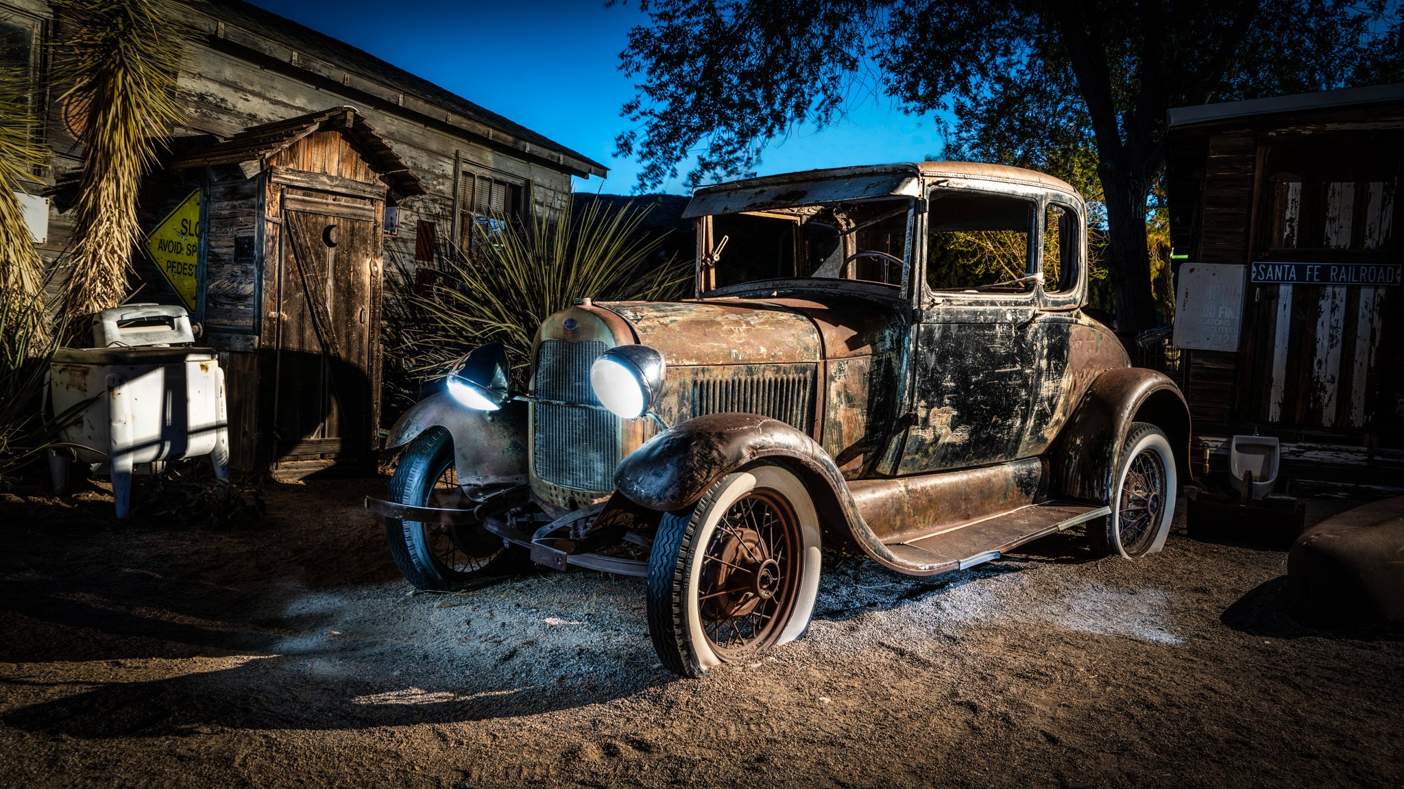 Limited edition fine art photograph by Jason Sponseller, featuring a weathered antique car outside a rustic Route 66 general store with glowing headlights, aged wood, desert textures, and nostalgic Americana atmosphere