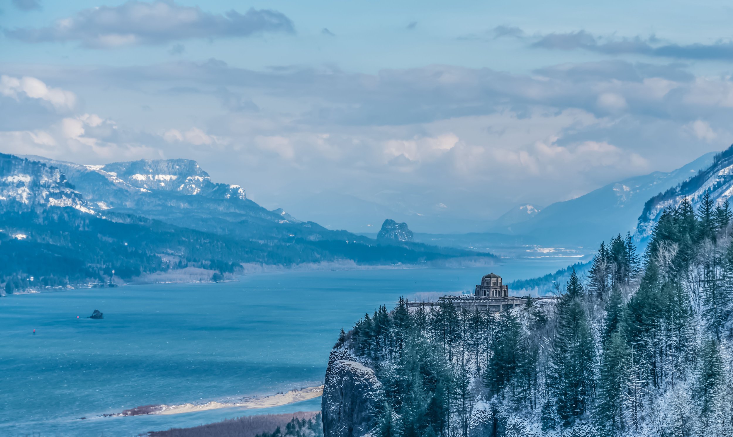 Dust and Distance: The Resonance of Time, limited edition fine art photograph by Jason Sponseller, featuring the Columbia River Gorge in winter with snow-covered forest, blue mountain ridges, river water, and quiet atmospheric distance