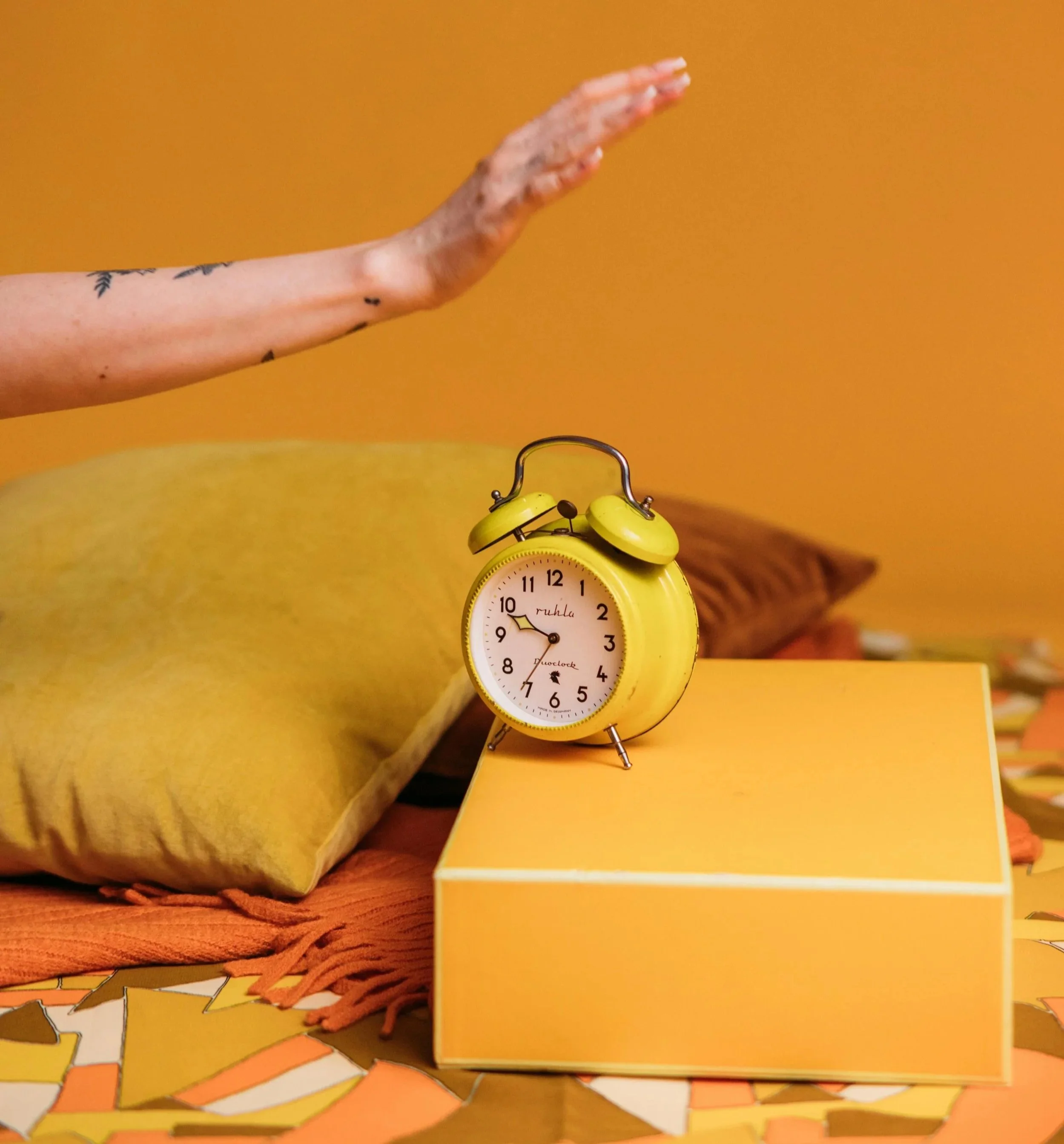 Stock photo of a hand over an alarm clock as if it's about to turn it off.
