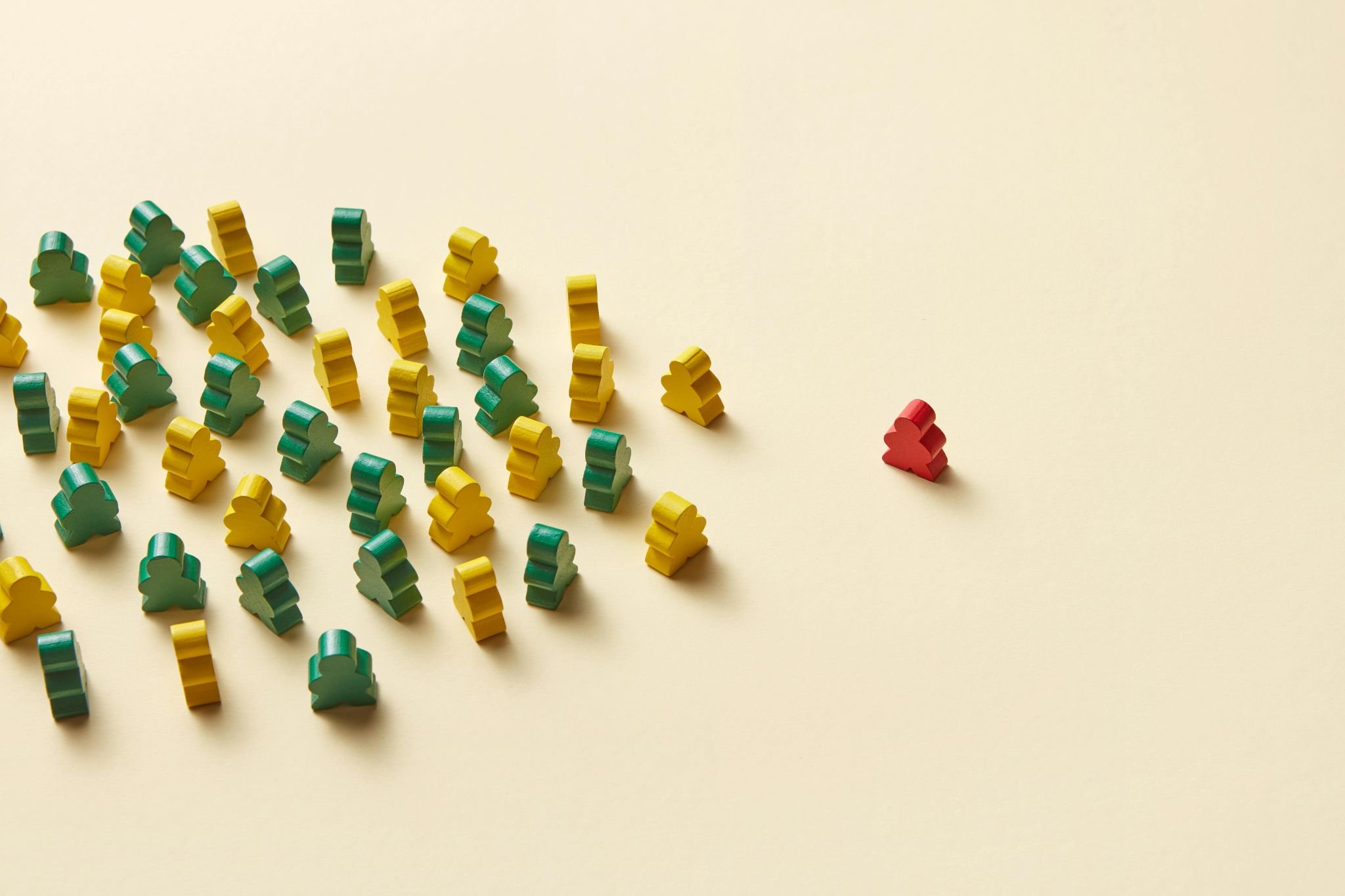 A stock photo of a pile of yellow and green game pieces on the left side of the photo and a single red game piece on the right.