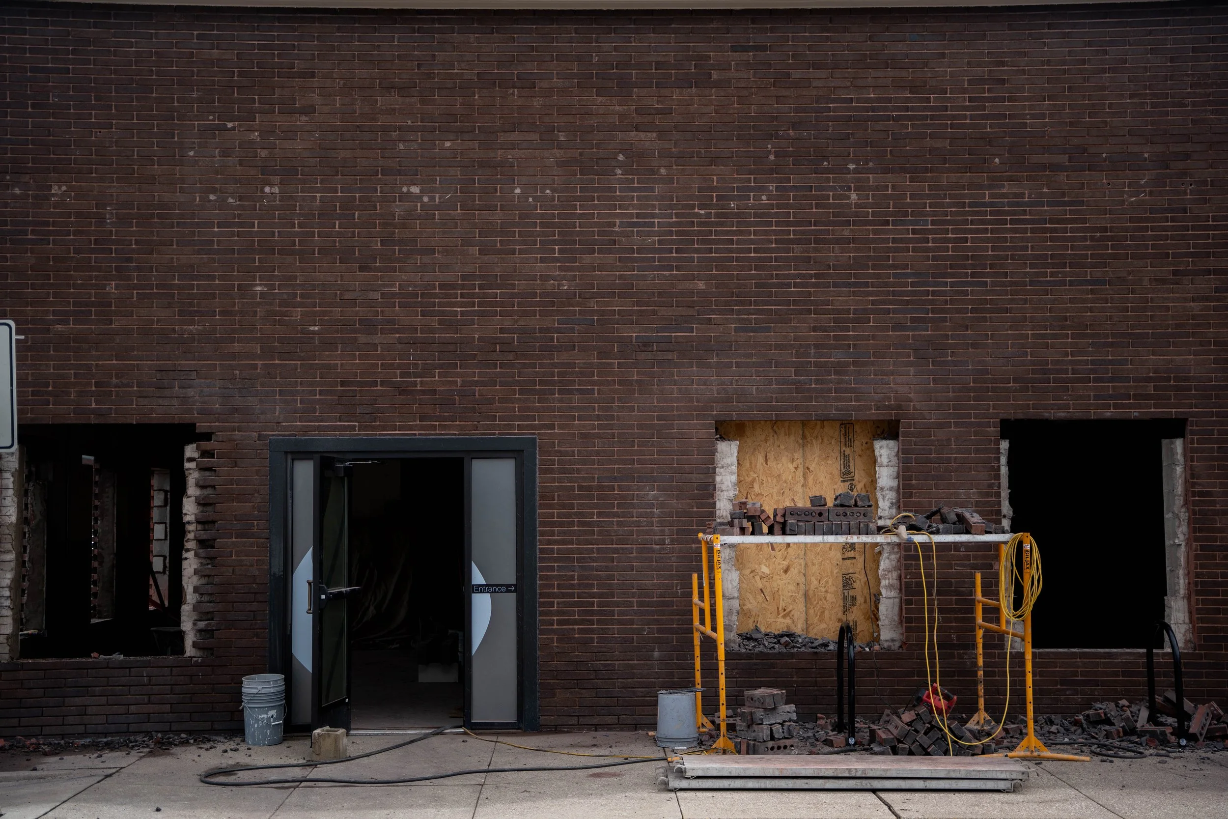 The Community Foundation building with a door propped open and windows cut out of brick walls. Scaffolding and tools are in the foreground.