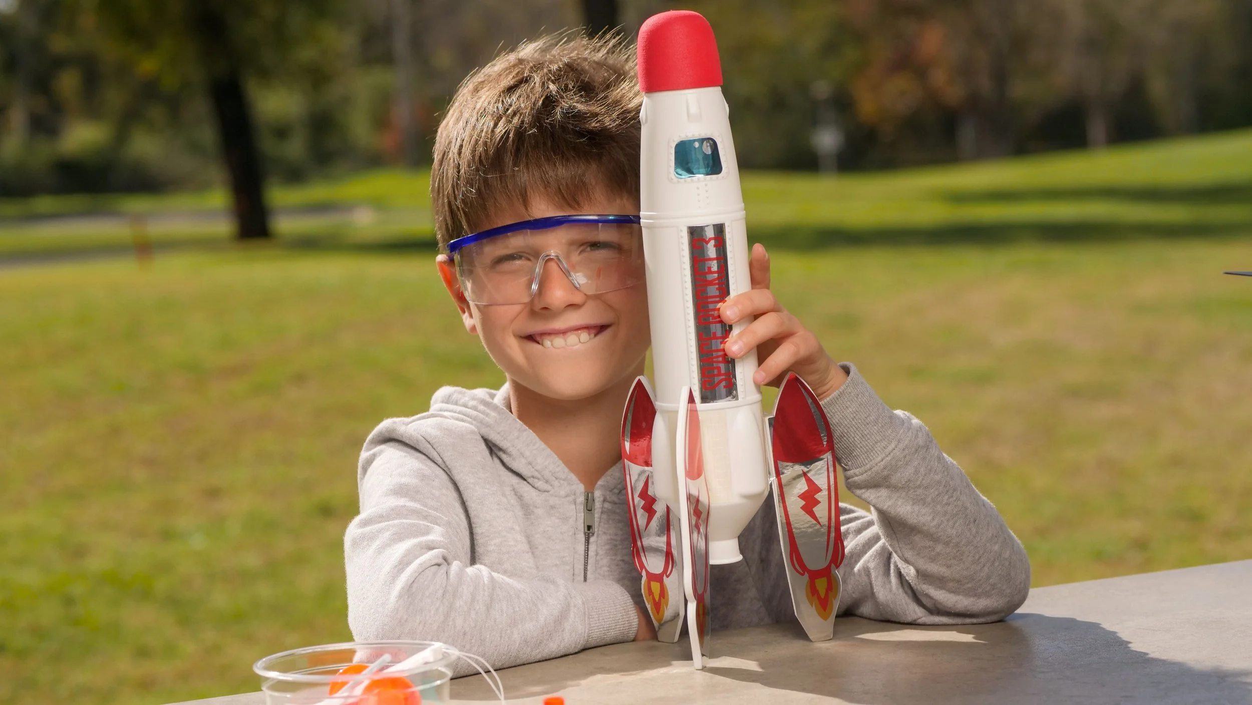 A little boy with safety goggles holding a toy rocket ready for take off.