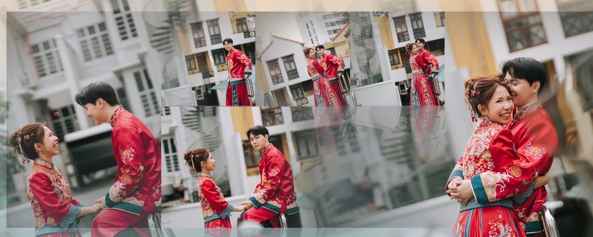 A young couple dressed in traditional red Chinese wedding attire holding hands and smiling, with the woman leaning into the man, in a residential neighborhood with multi-story houses in the background.