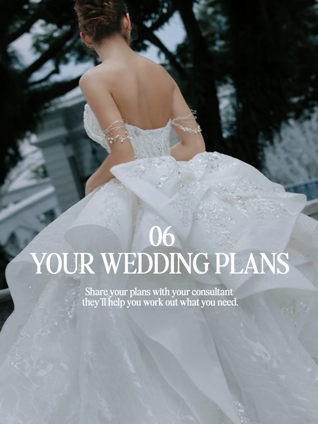 Back view of a bride in a corset ball gown with pearl arm drapes and layered ruffle skirt